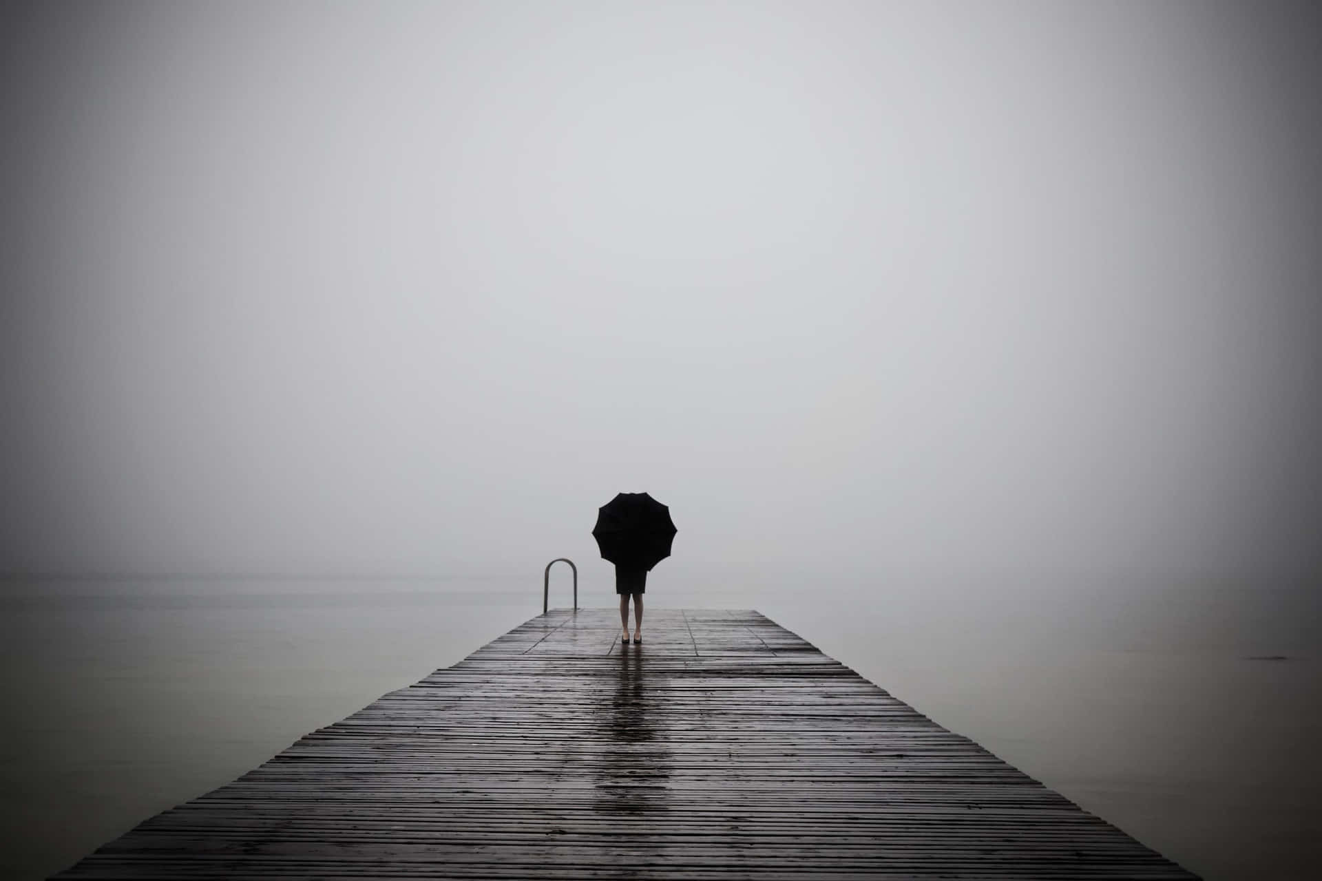 A Person Walking On A Dock In The Fog
