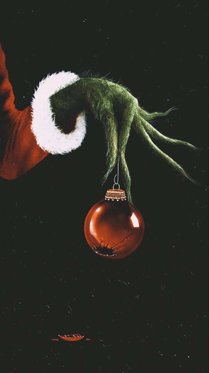 Grinch Hand Holding Christmas Ornament Wallpaper