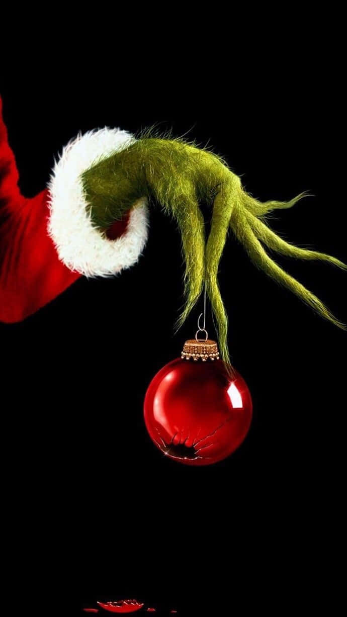 Grinch Hand Holding Christmas Ornament Wallpaper