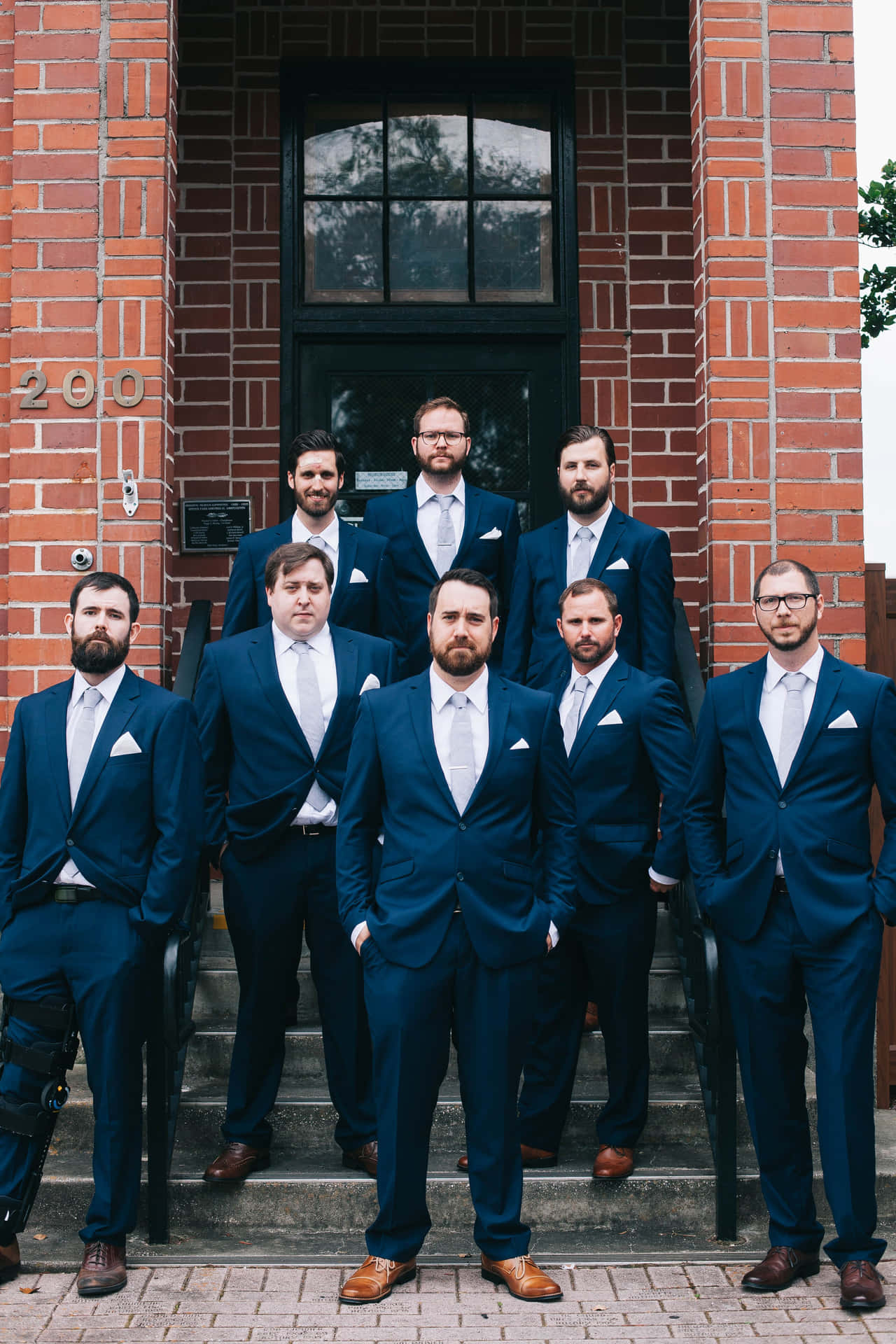 A Group Of Groomsmen Standing Outside A Brick Building