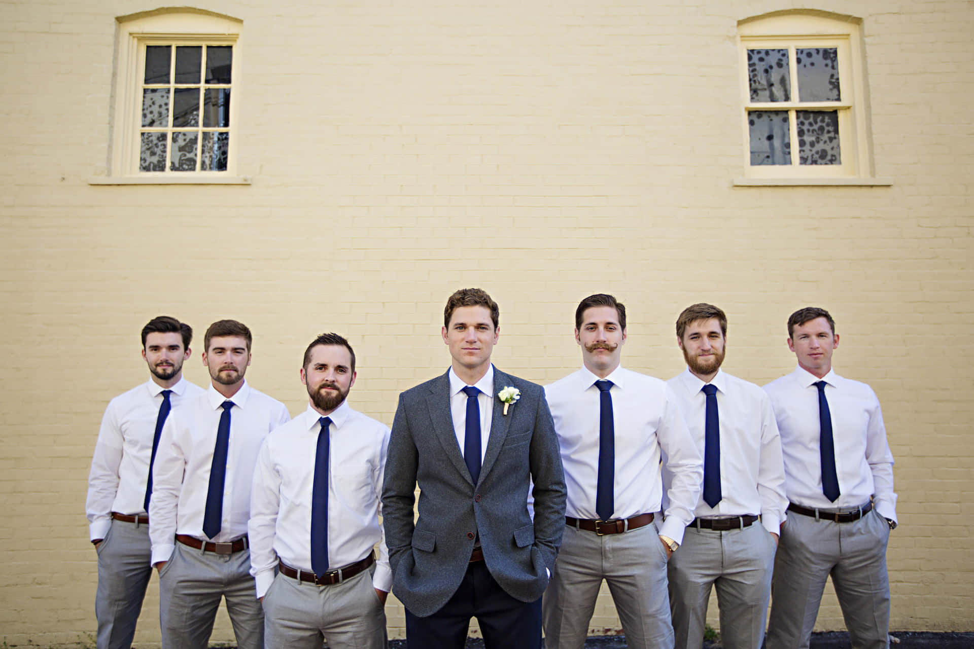 A Group Of Groomsmen Standing In Front Of A Building