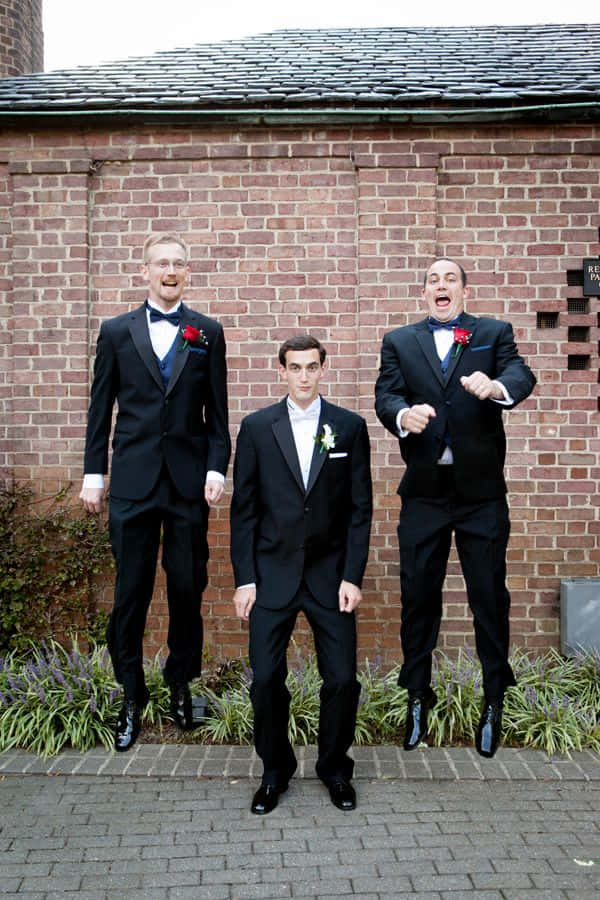 Three Groomsmen In Tuxedos Jumping For The Camera