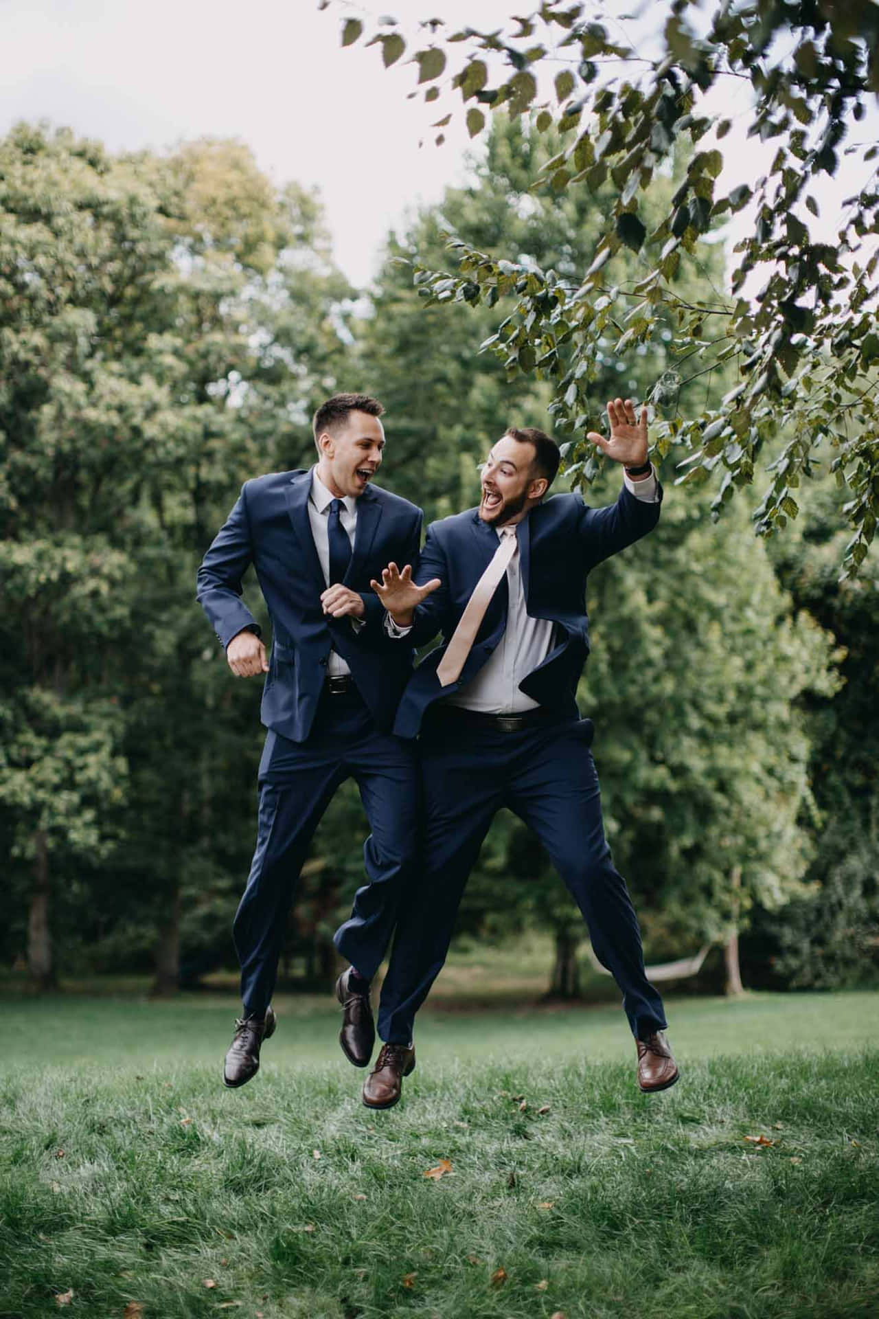 Two Groomsmen Jumping In The Air In A Park