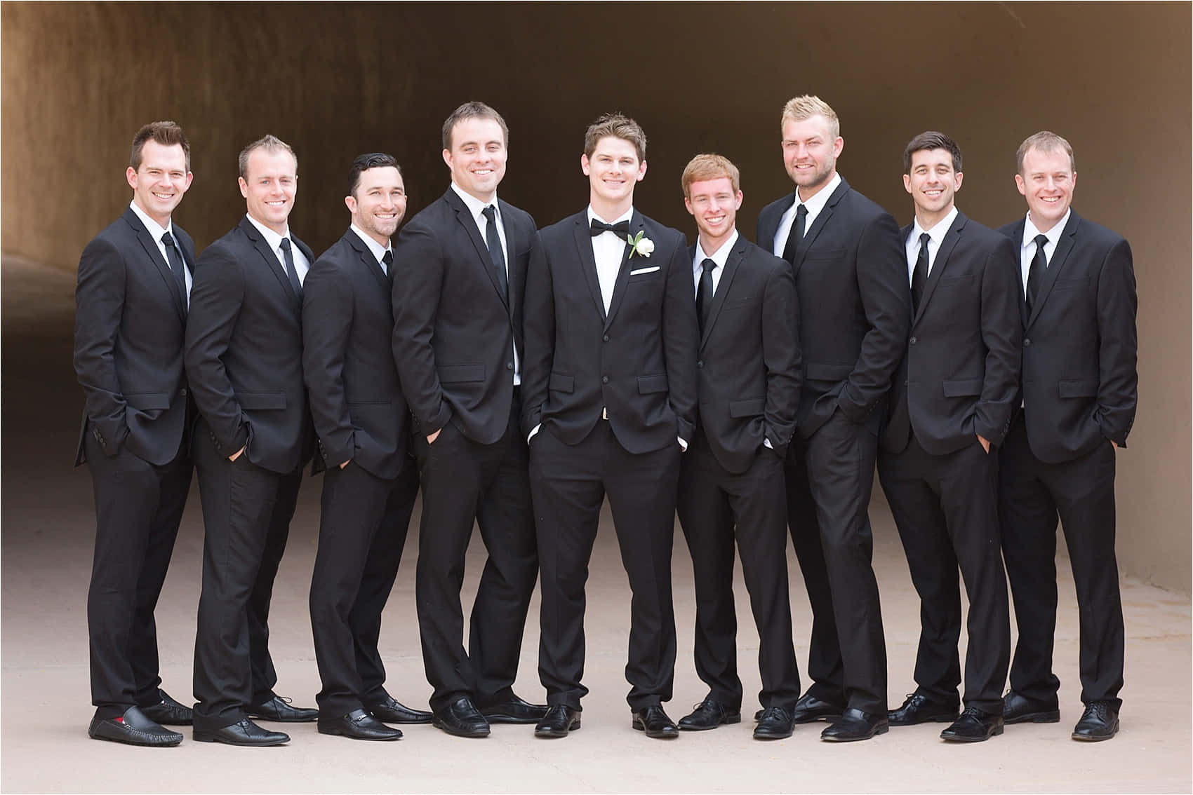 A Group Of Groomsmen In Black Suits Posing For A Photo
