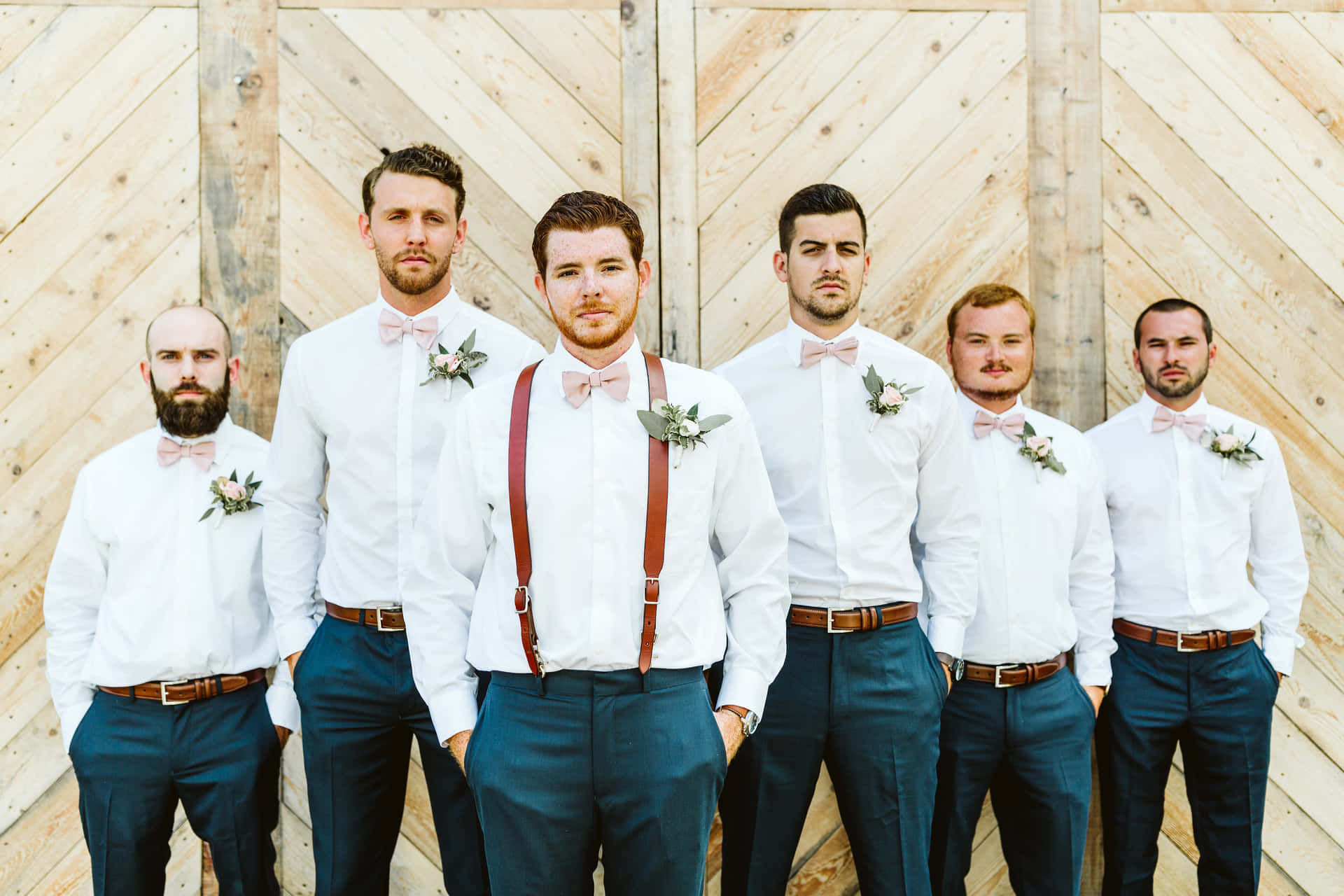 A Group Of Groomsmen Standing In Front Of A Wooden Wall