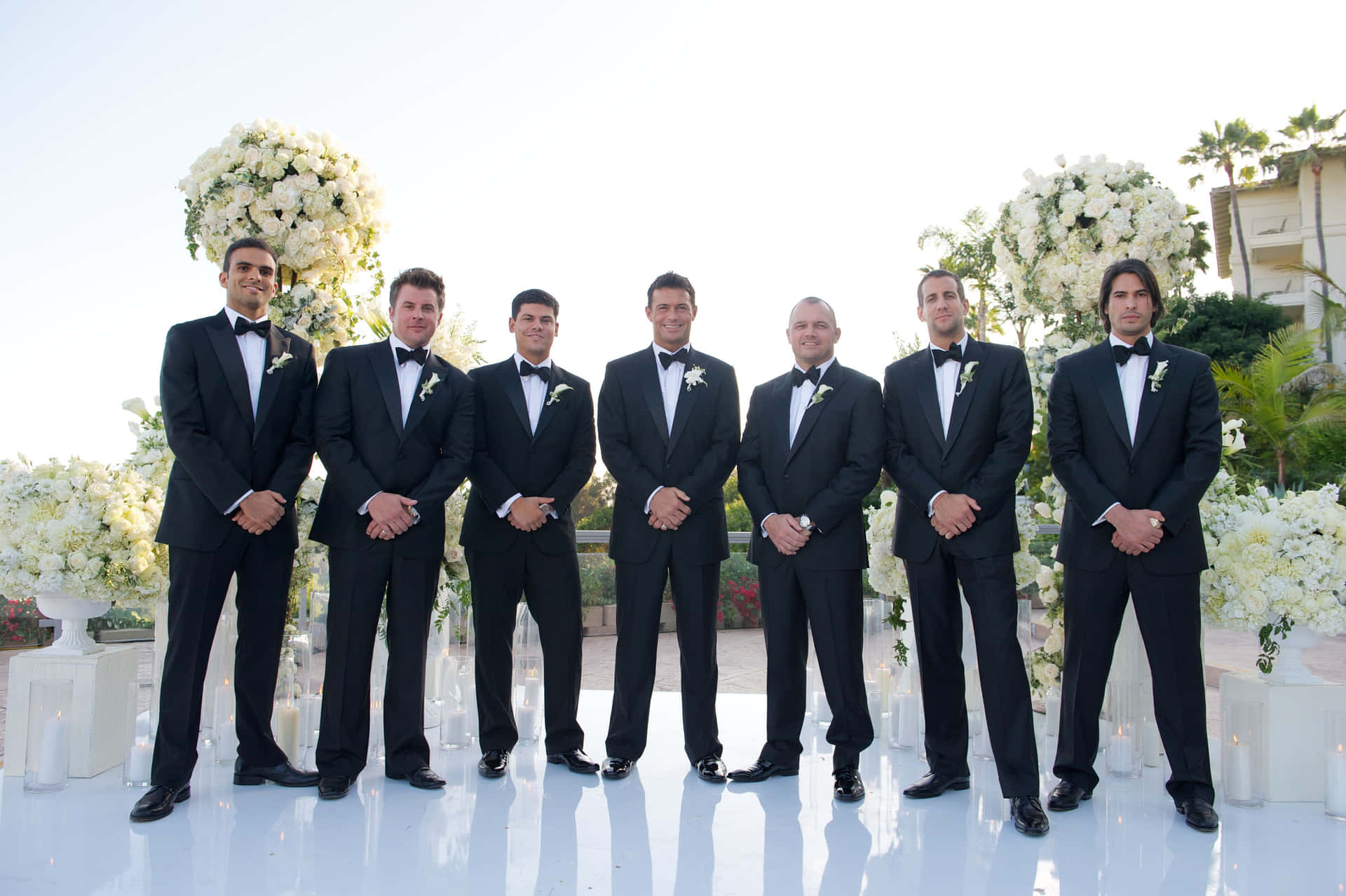 A group of five dressed up groomsmen posing together at a wedding.