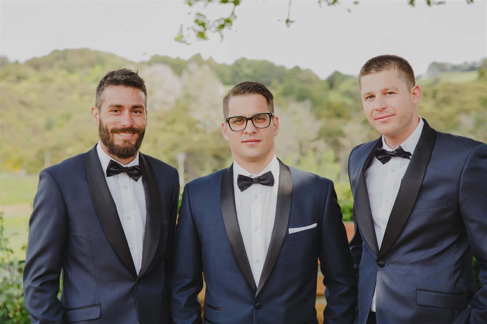 Three Groomsmen In Tuxedos Standing Together