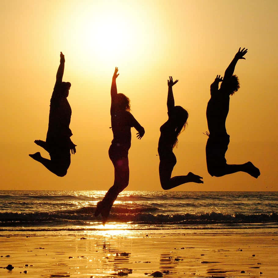 Grupode Amigos Saltando En La Playa. Fondo de pantalla