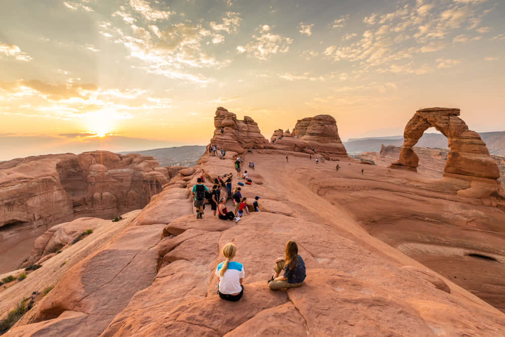 Group Travelers At Delicate Arch Wallpaper