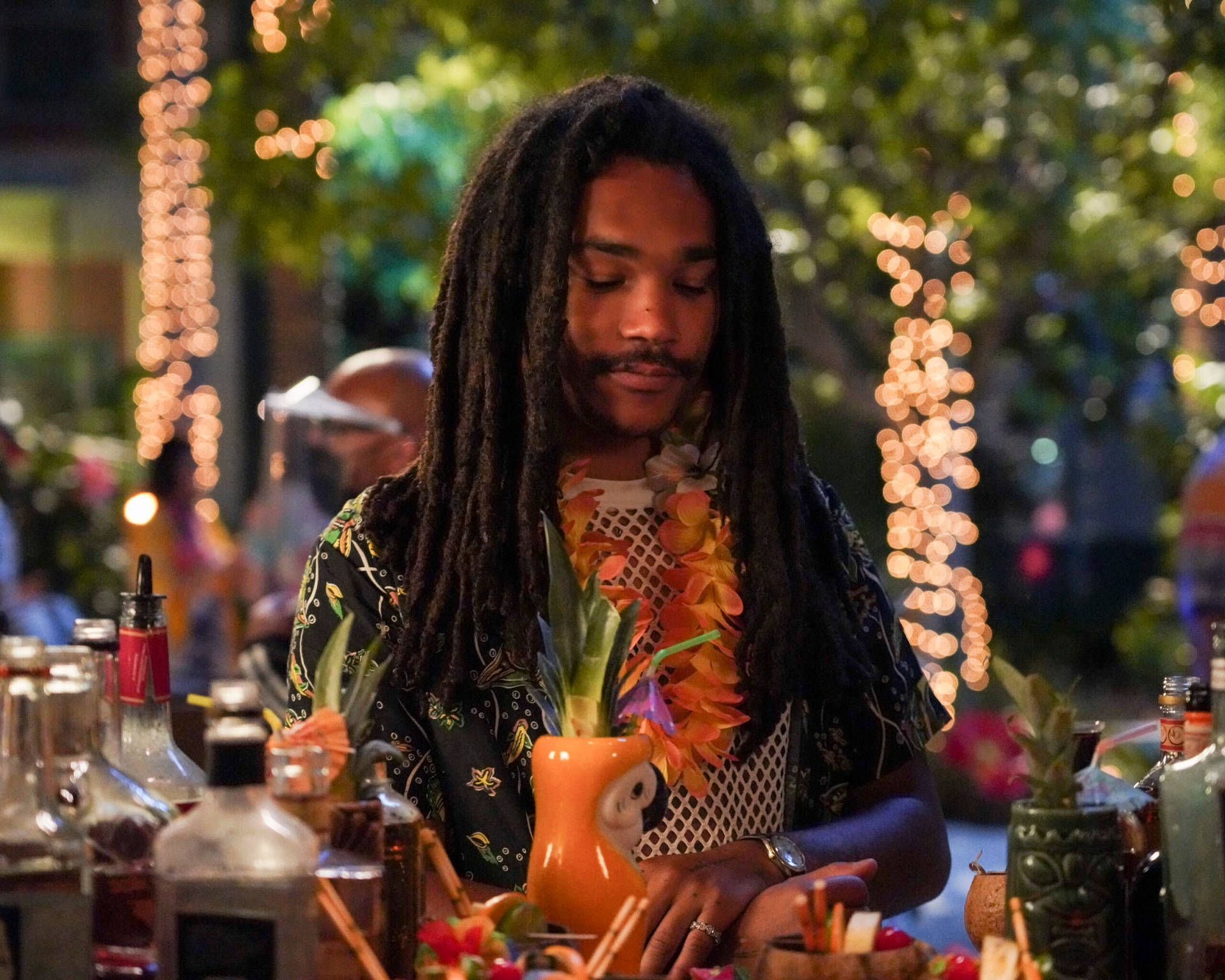 A Man With Dreadlocks Is Making Drinks At A Bar Wallpaper