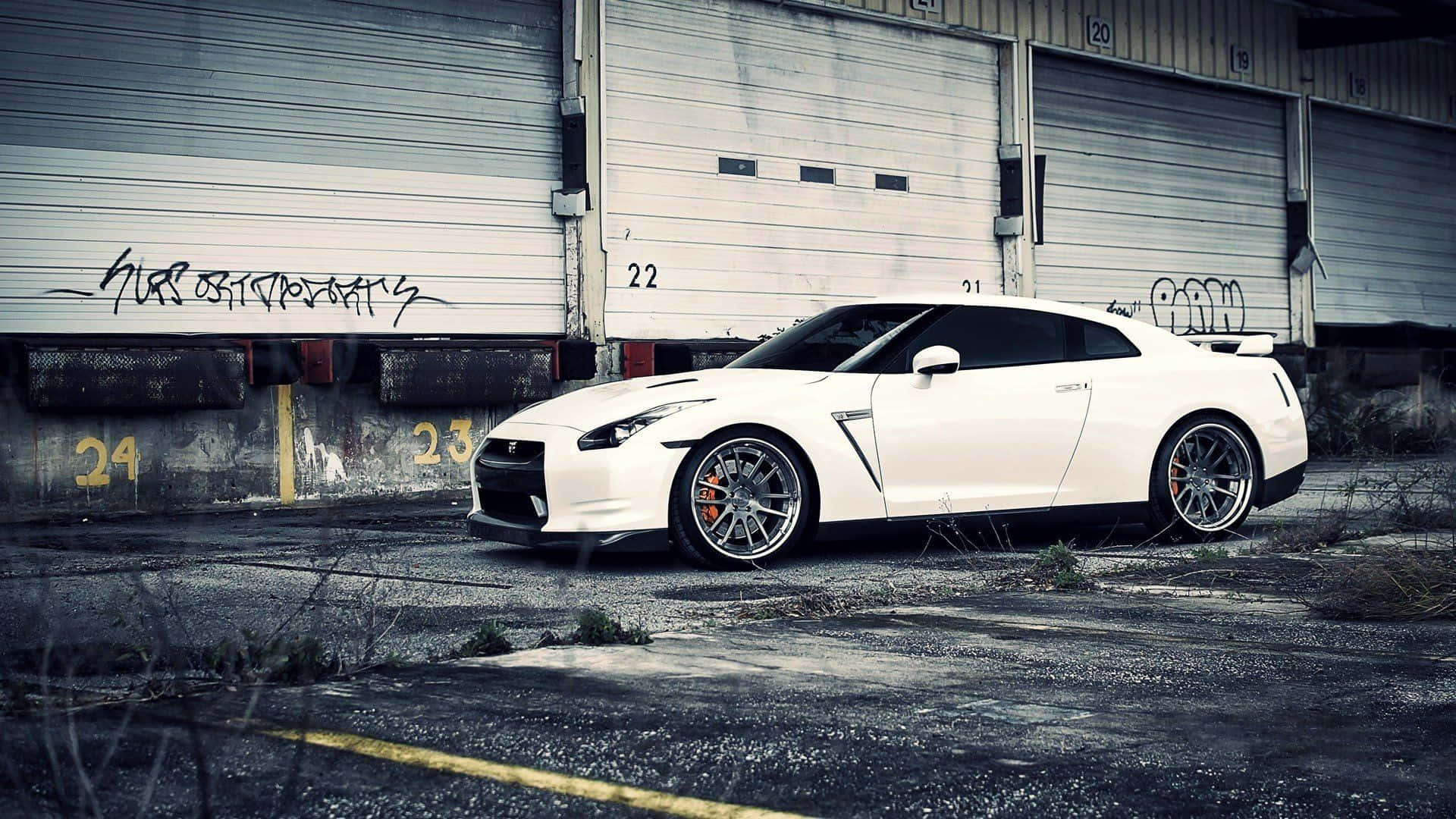A White Nissan Gtr Parked In Front Of A Garage Wallpaper