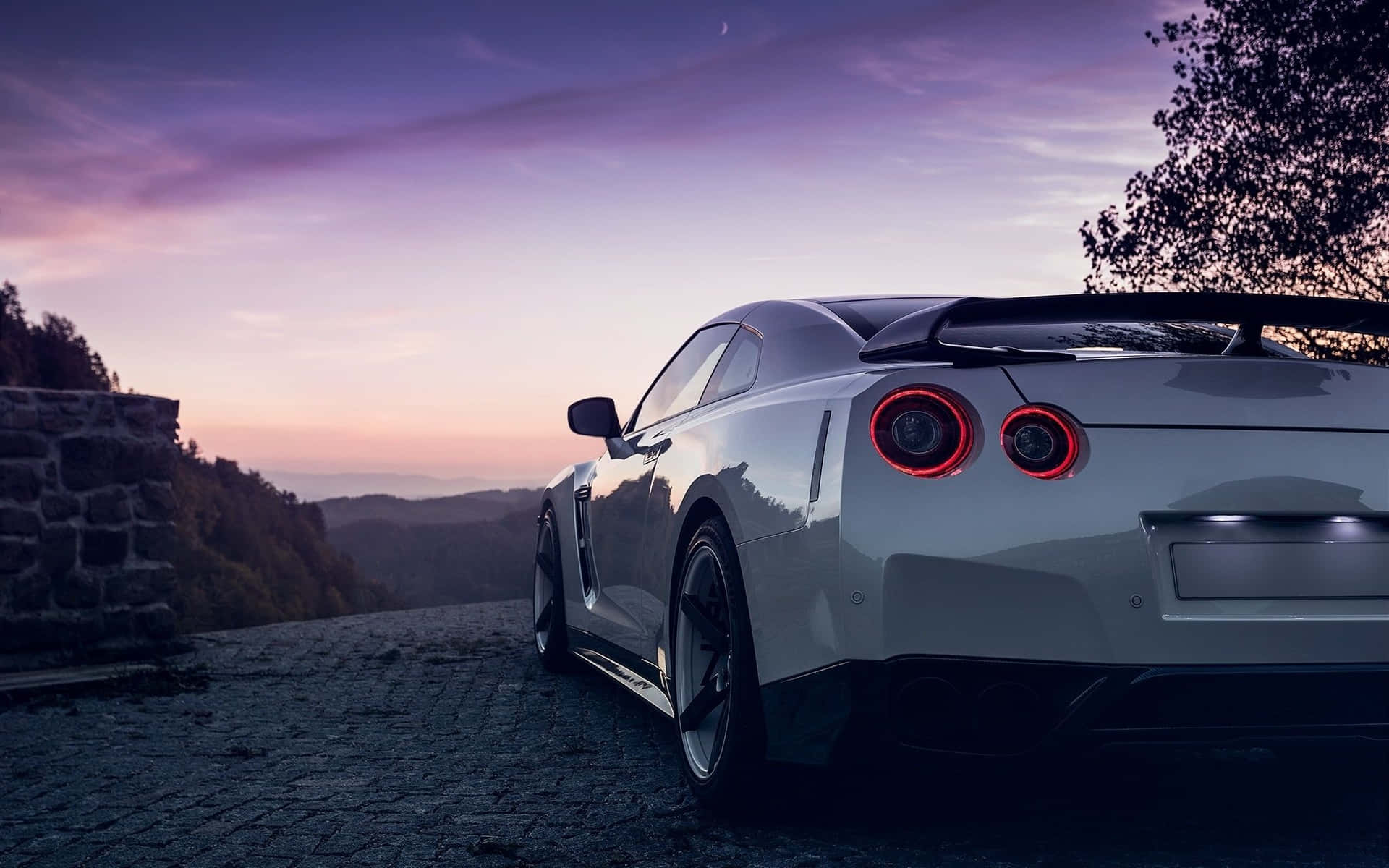 A White Sports Car Parked On A Road At Sunset Wallpaper