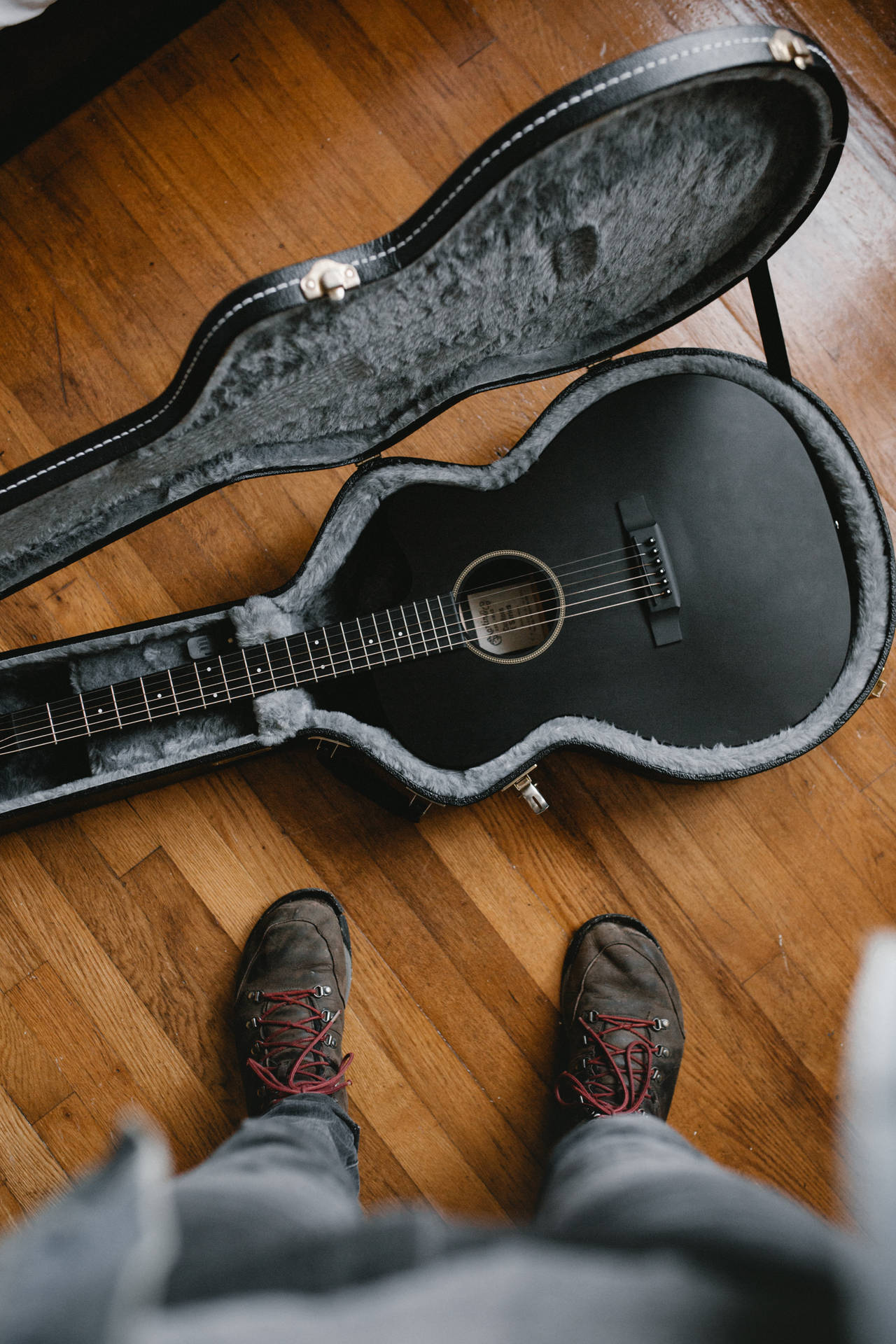 An All-Black Guitar Sitting on a Floor Wallpaper