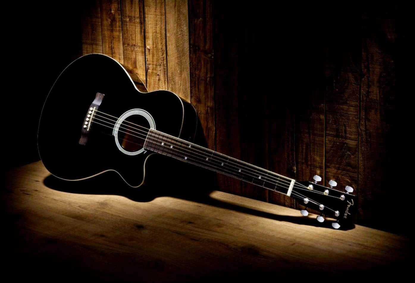 A Black Acoustic Guitar Is Sitting On A Wooden Table