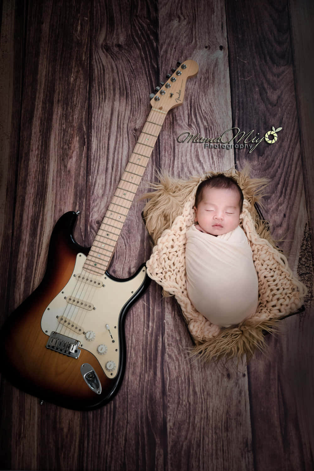 En nyfødt baby ligger ved siden af en elektrisk guitar