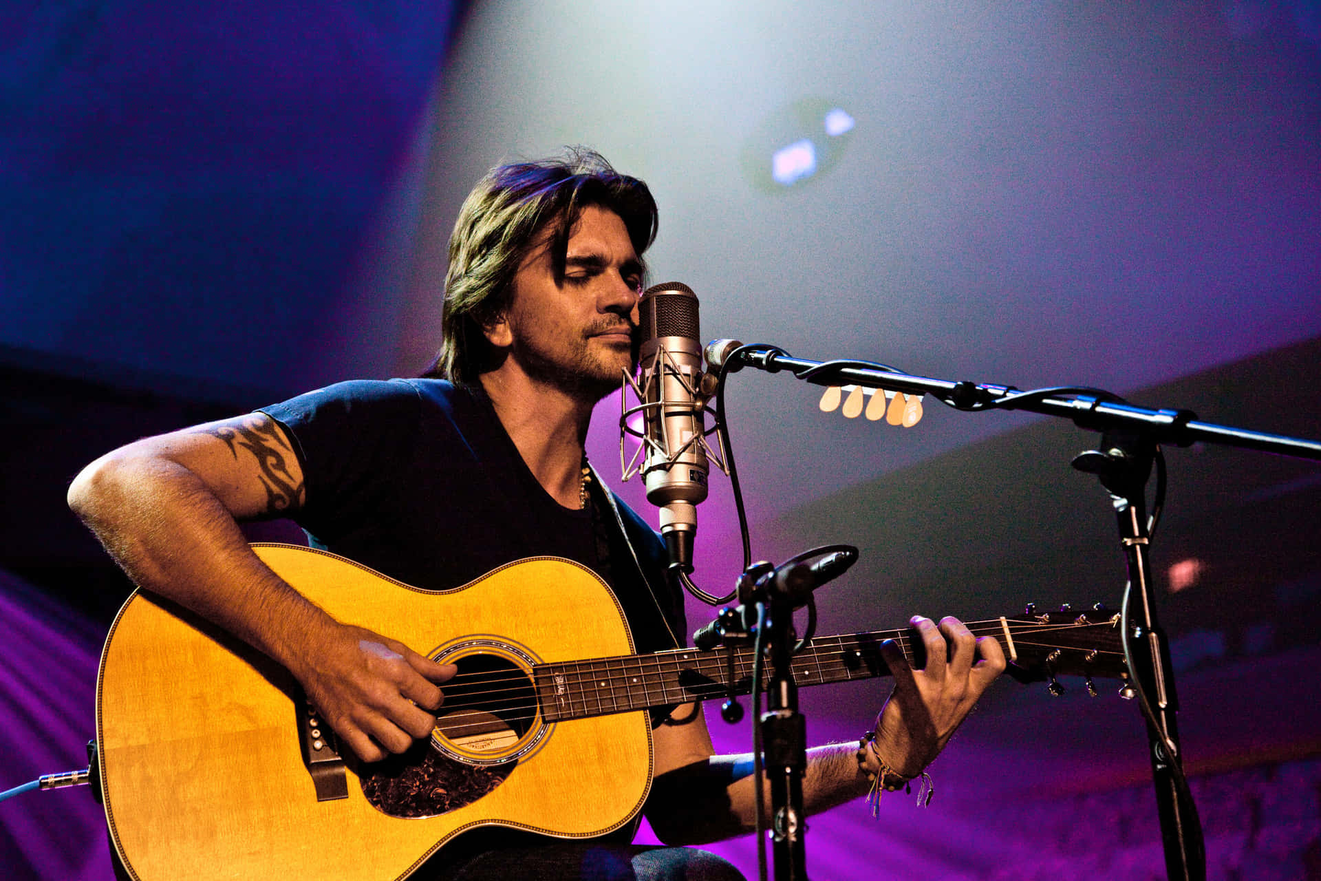 A Man Playing An Acoustic Guitar In Front Of A Microphone