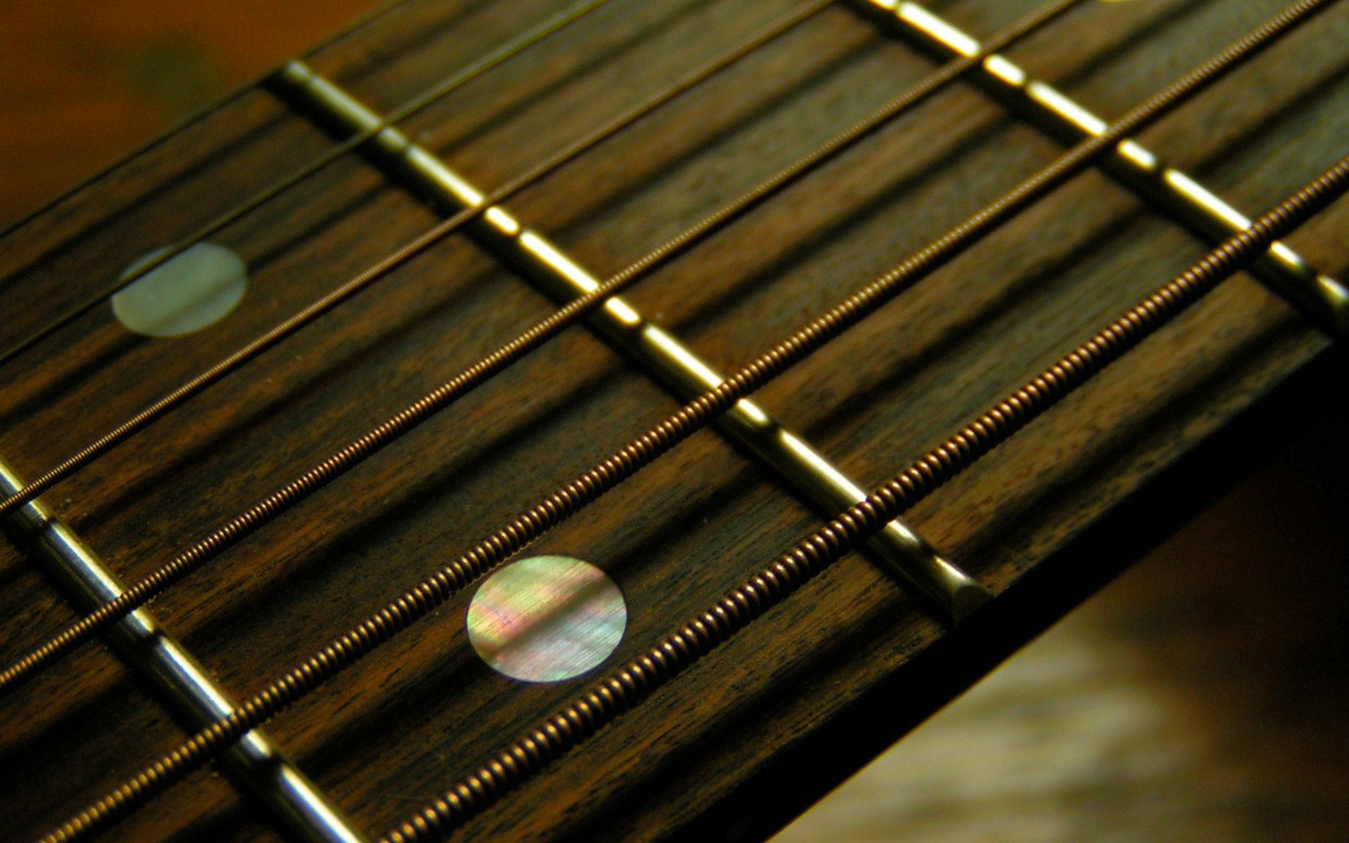 A Close Up View of Fretboard Strings on a Guitar Wallpaper