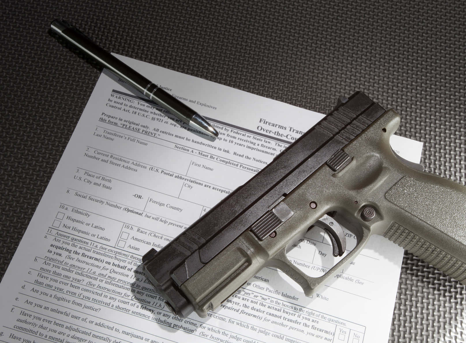 A Gun Is Sitting On Top Of A Form Of Identification