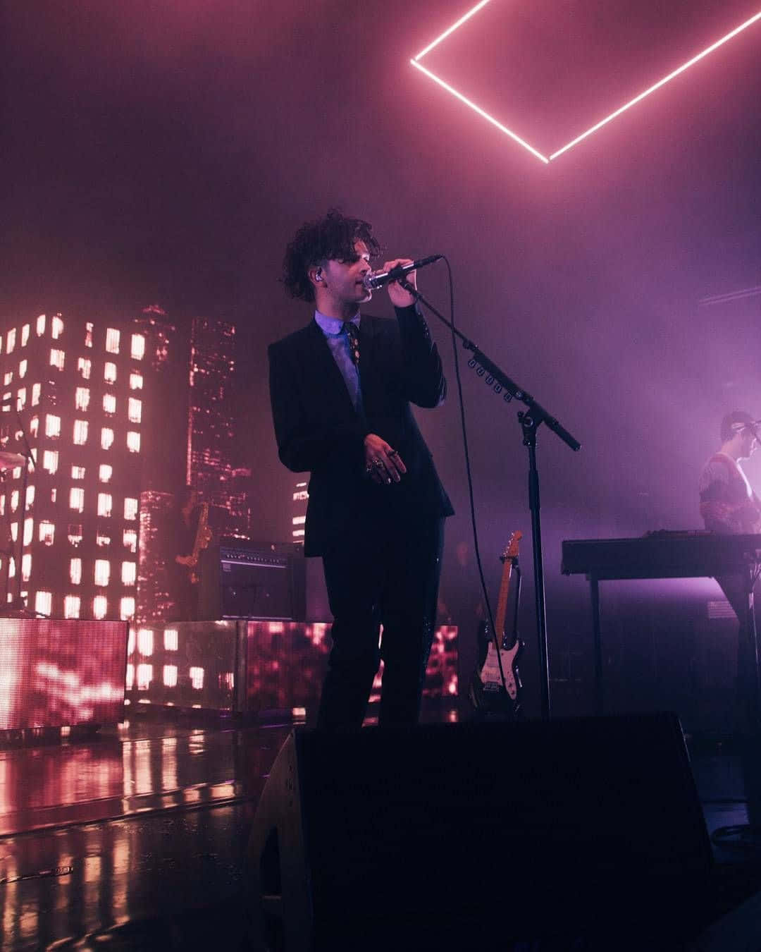 A Man In A Suit Singing On Stage Wallpaper