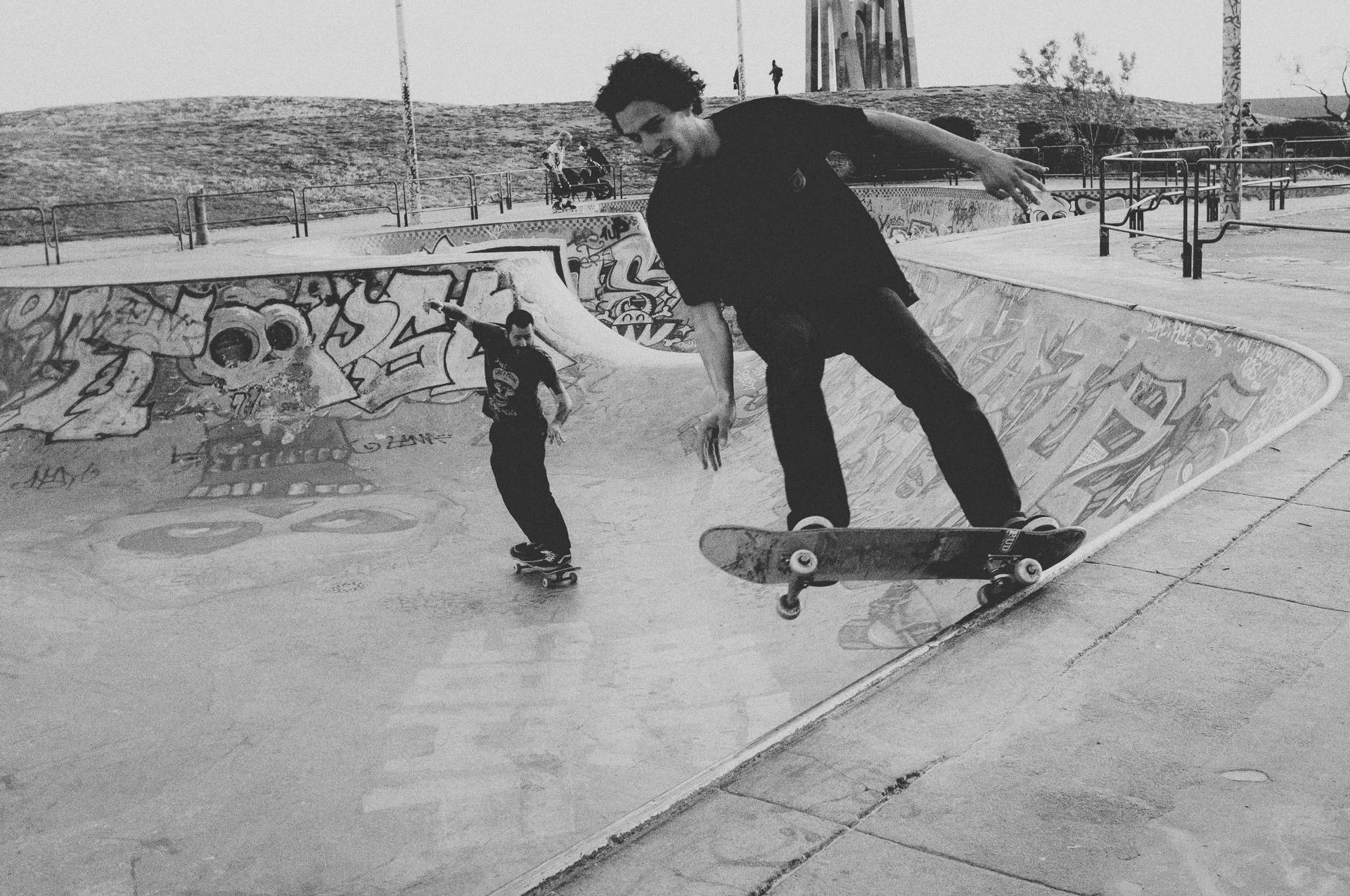 A couple of friends skateboarding together in black and white Wallpaper