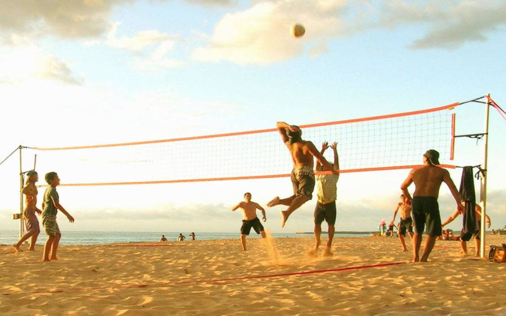 Guys Playing Beach Volleyball On A Sunny Day Wallpaper