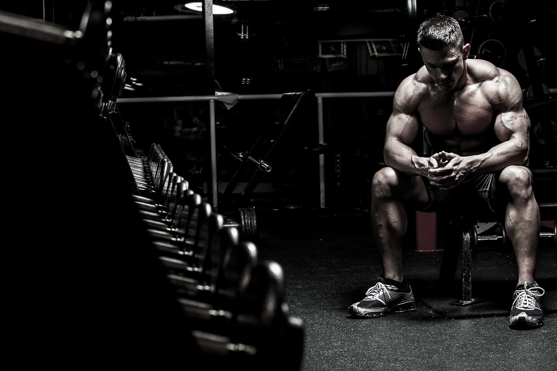 A Man Sitting On A Bench In A Gym