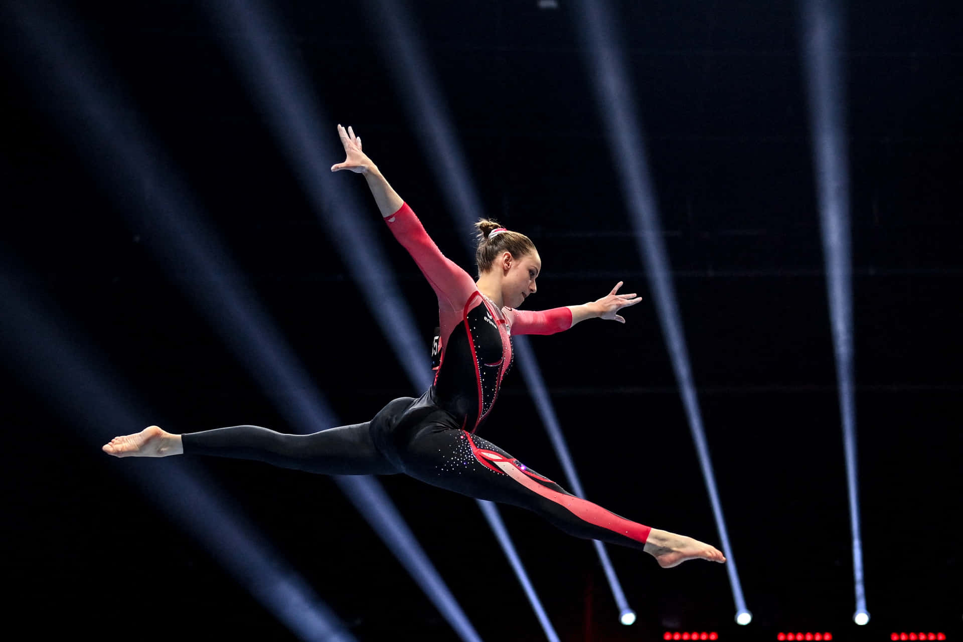 A Gymnast In The Air With Lights On Her Face