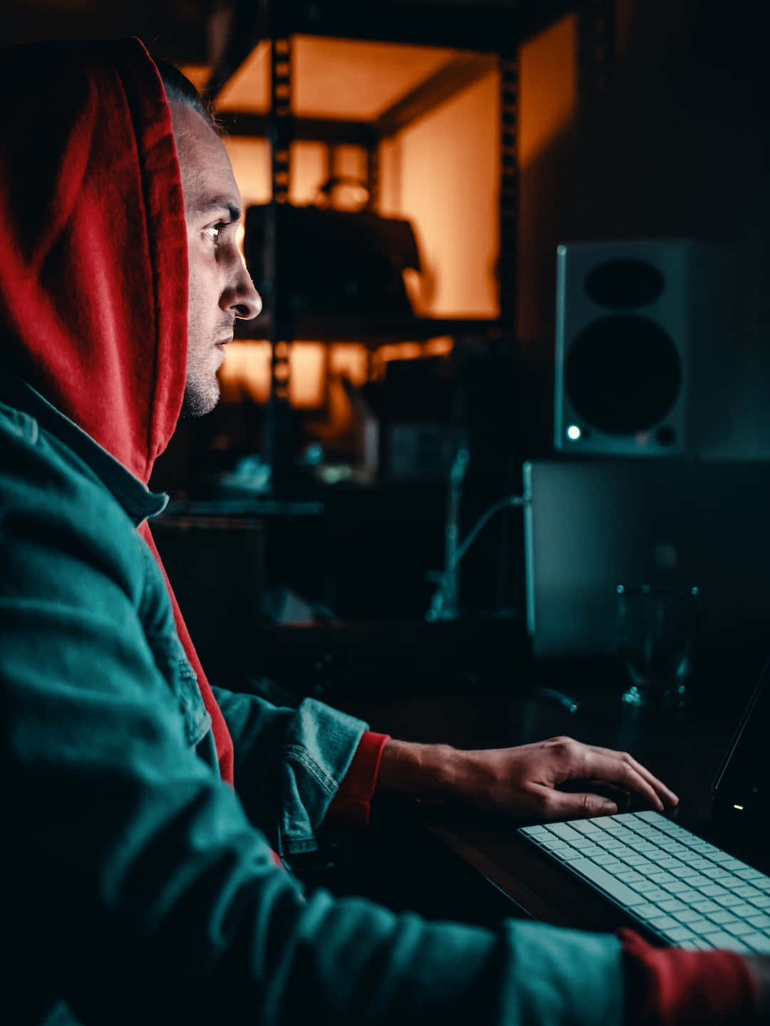A Man In A Red Hoodie Sitting At A Desk