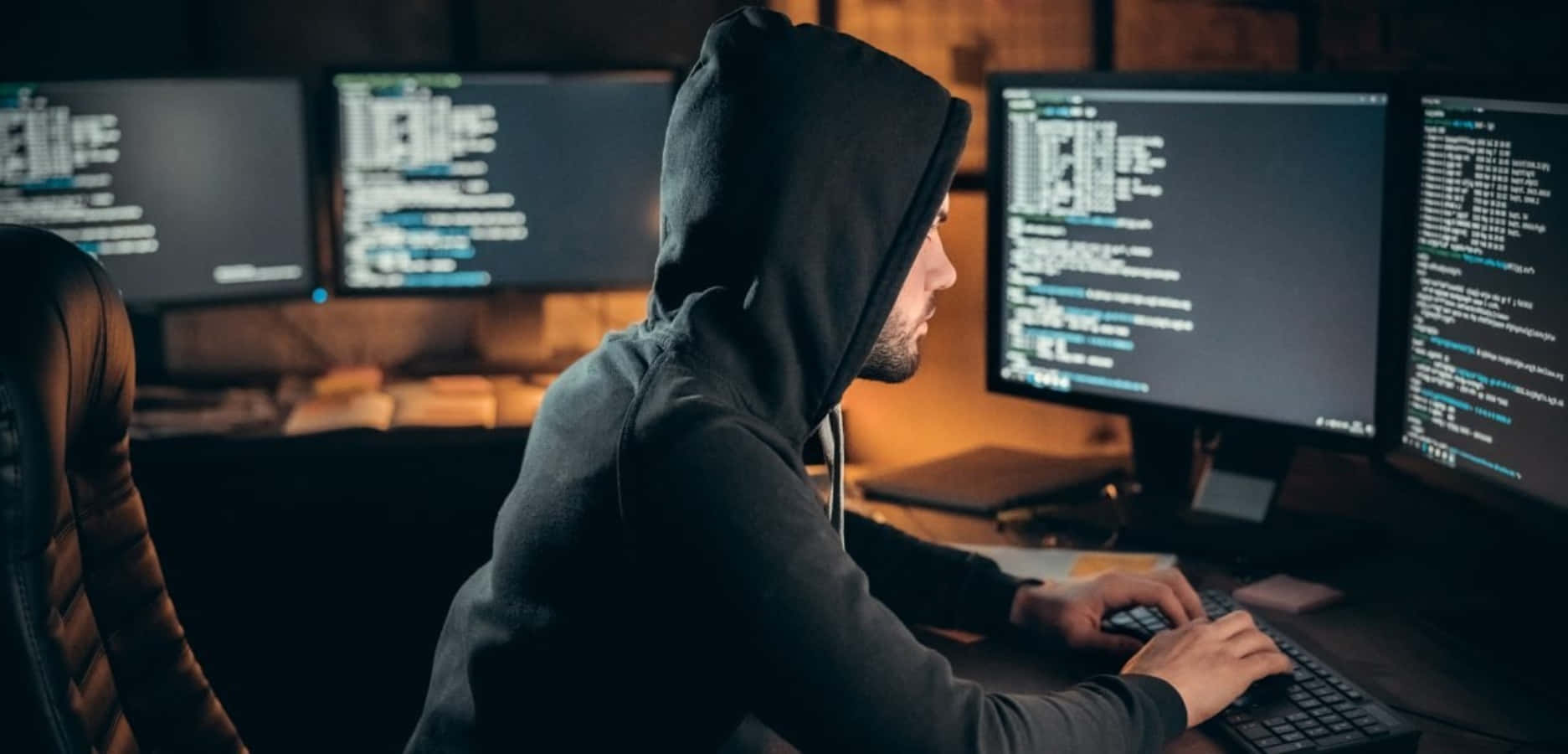 A Man In A Hoodie Is Working On A Computer