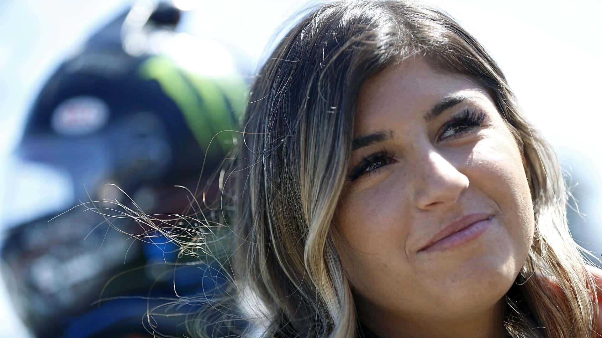 Hailie Deegan Glimlachend Met Helm Achtergrond