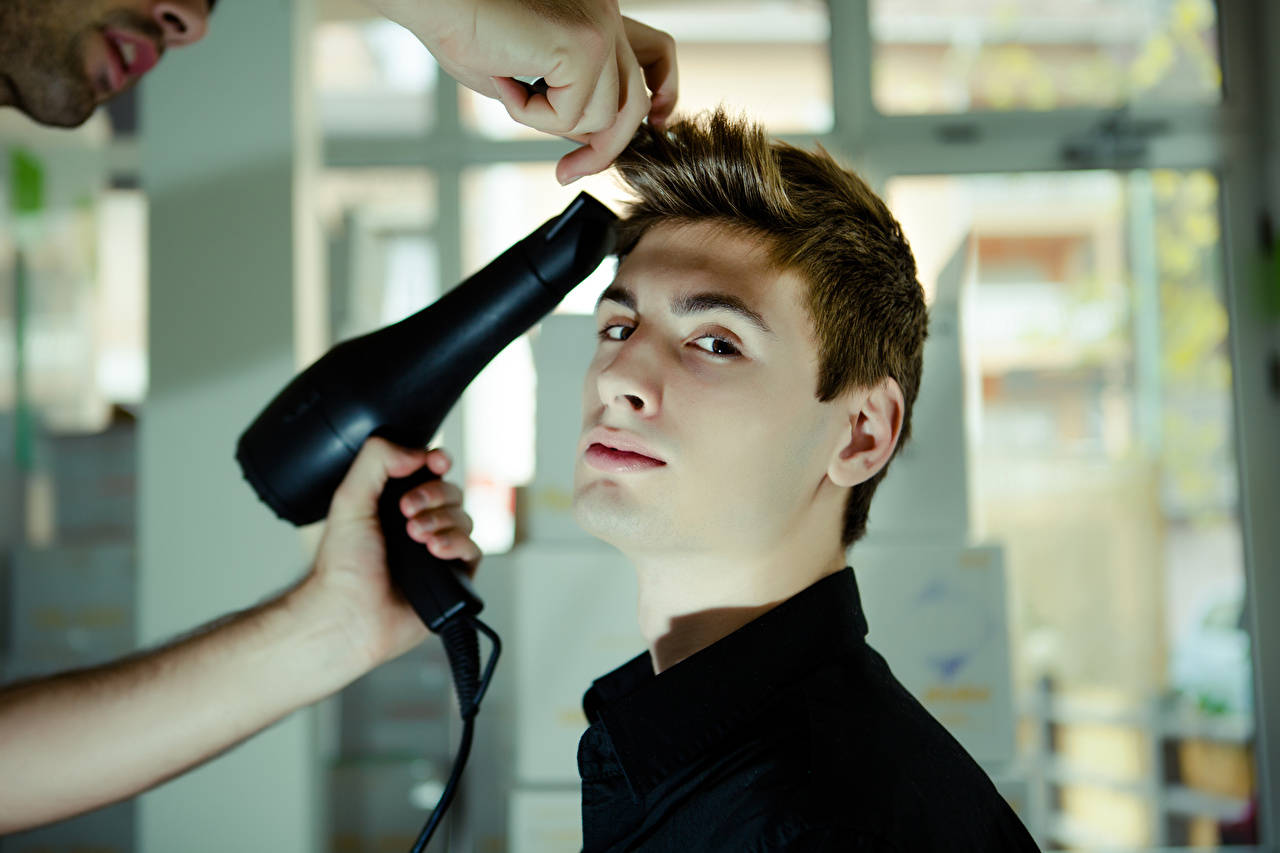 A man experiencing a professional hairstyling session aiming for a fashionable cowlick style. Wallpaper