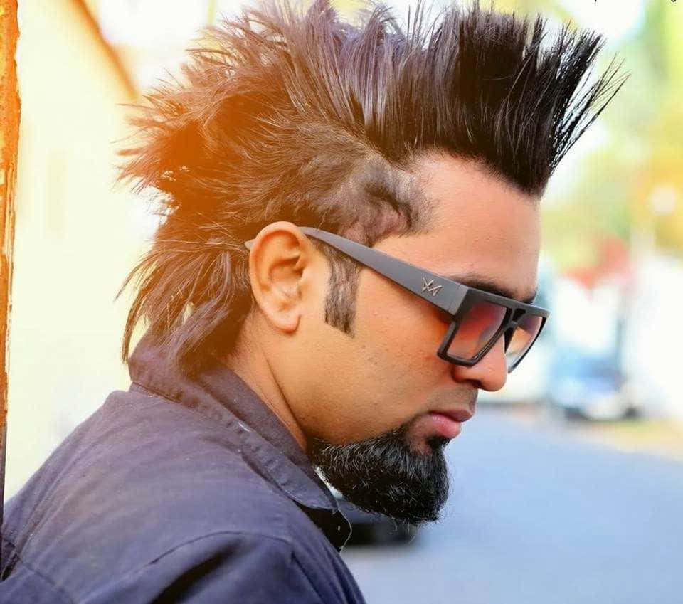 A Man With A Mohawk And Glasses Is Looking At The Camera
