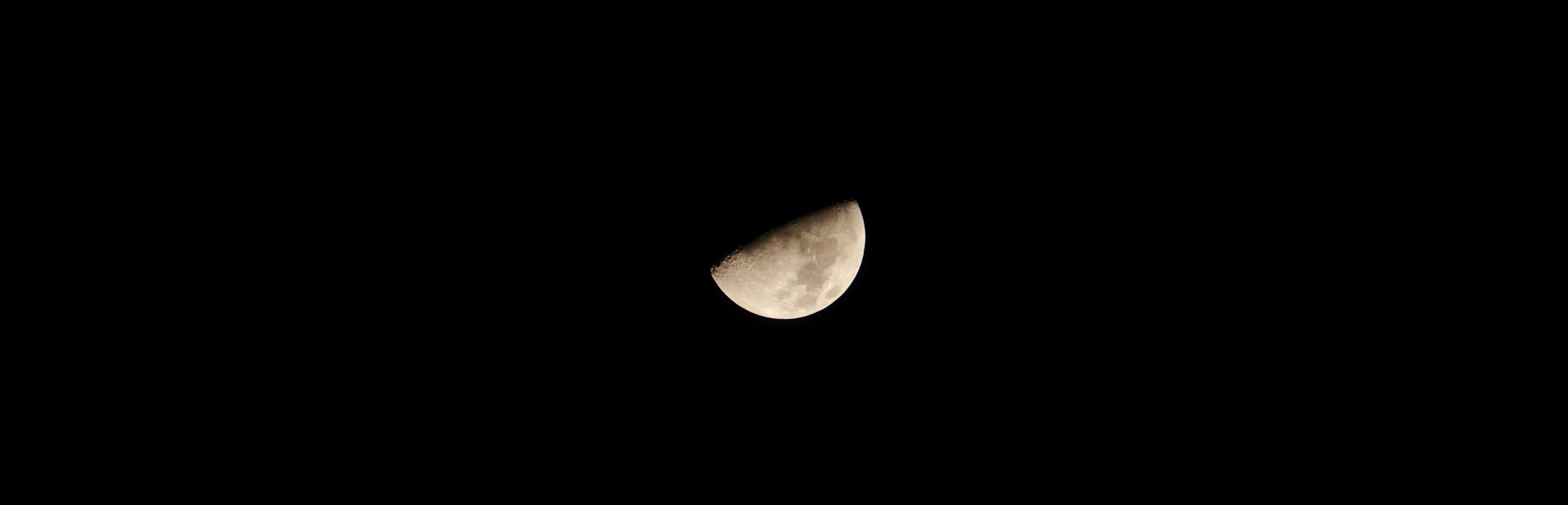 A radiant half-moon illuminated against a brilliant night sky.