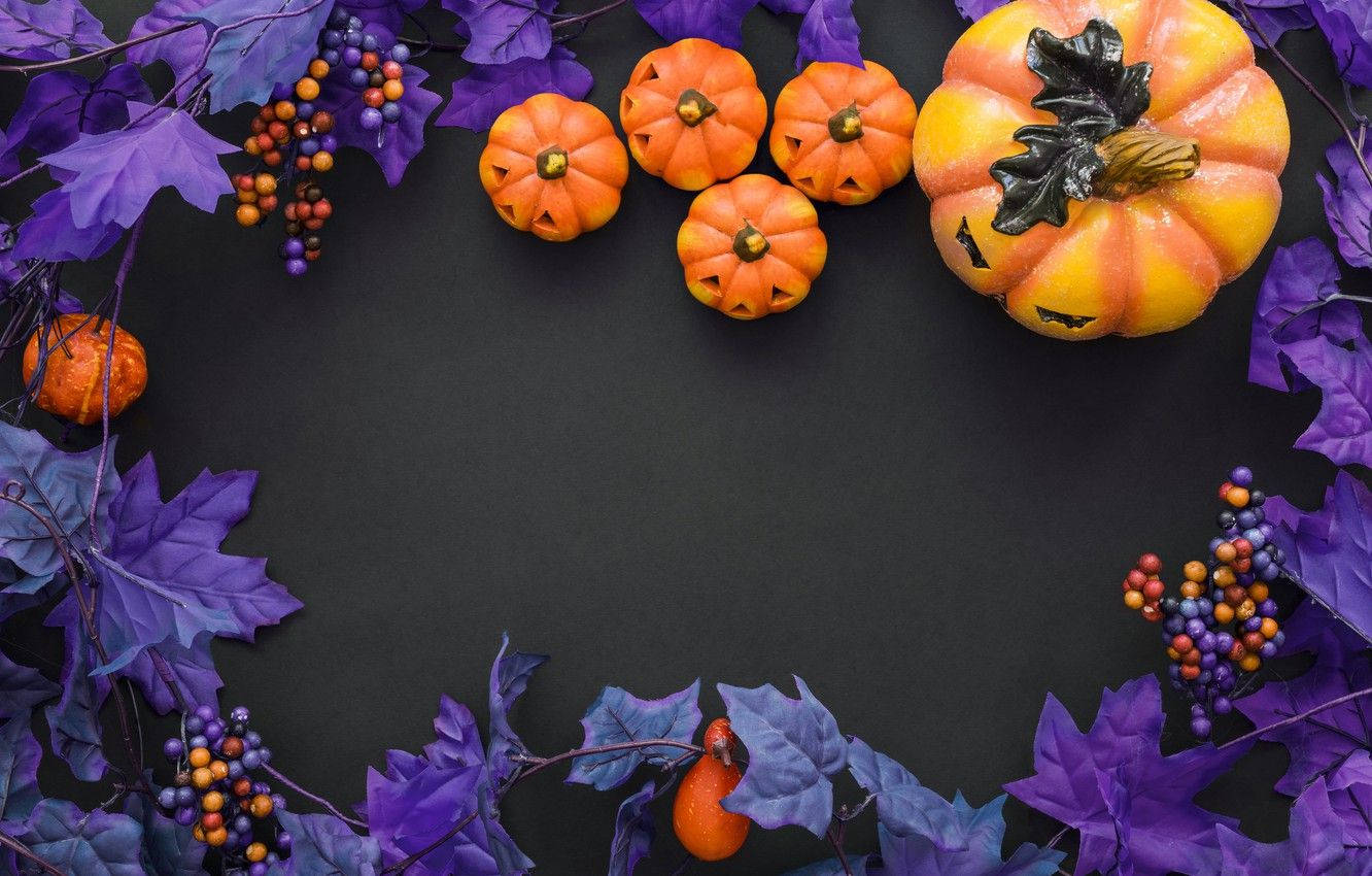 En Halloween-krans med gulerødder og lilla blade på en sort baggrund Wallpaper