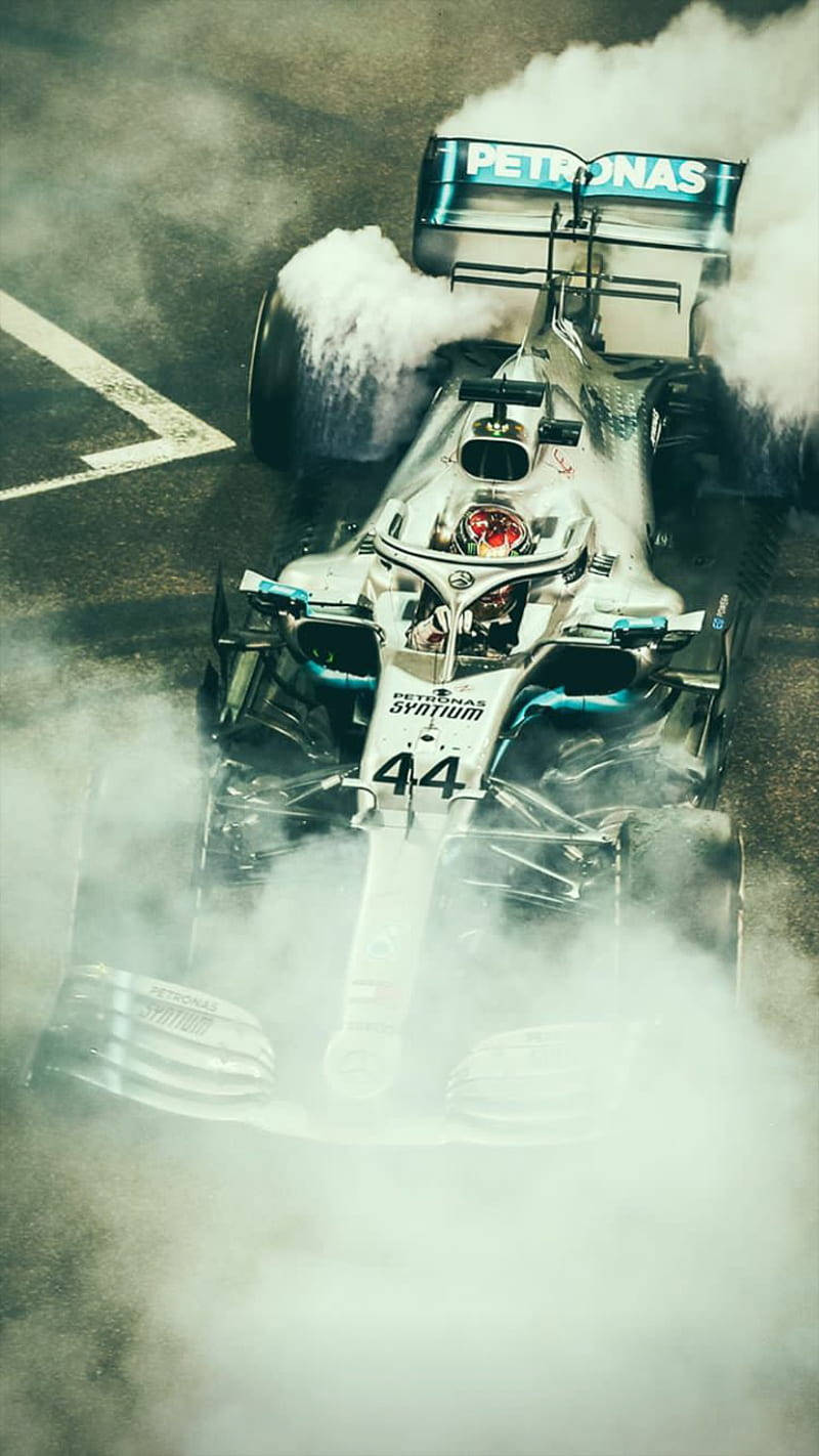 Cochede Carreras De Lewis Hamilton De Fórmula 1 Cubierto De Humo. Fondo de pantalla