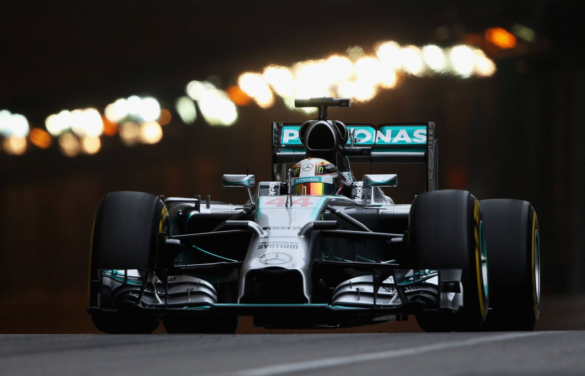 En Mercedes F1-bil kører på en bane om natten. Wallpaper