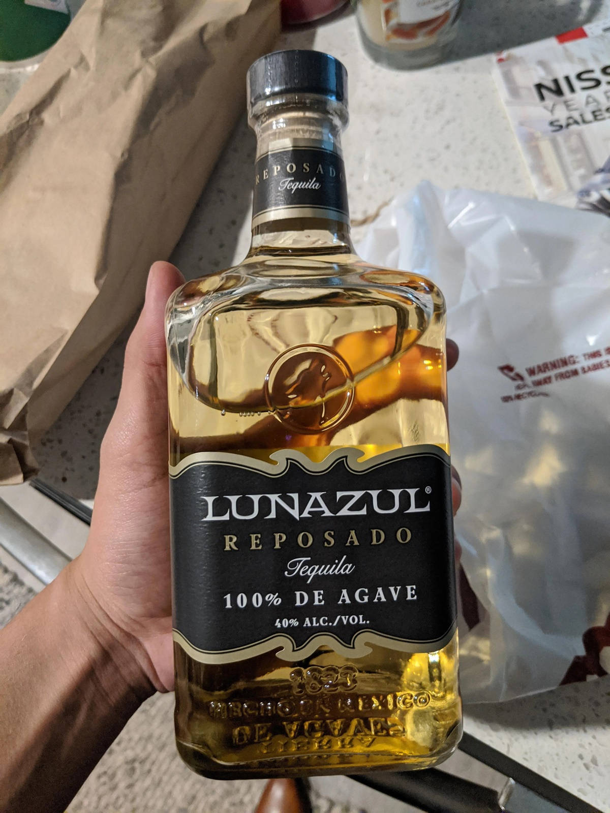 En hånd holdende Lunazul Reposad Tequila Wallpaper