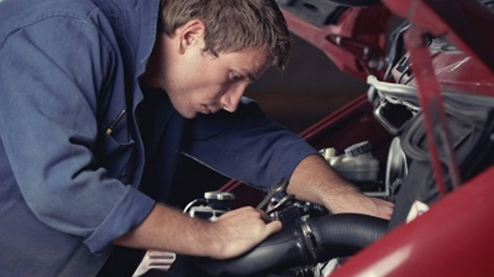 Skilled Professional Mechanic Inspecting a Car Engine Wallpaper