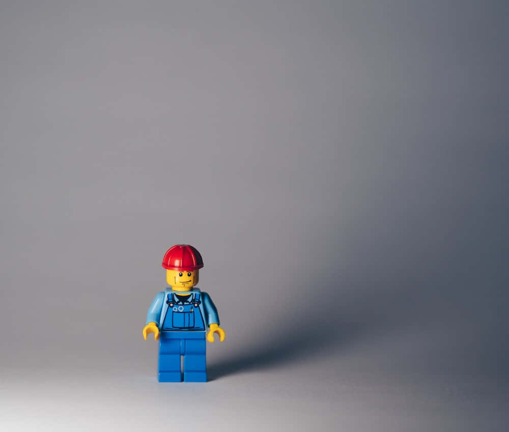 Unafigura Di Lego È In Piedi Su Uno Sfondo Grigio