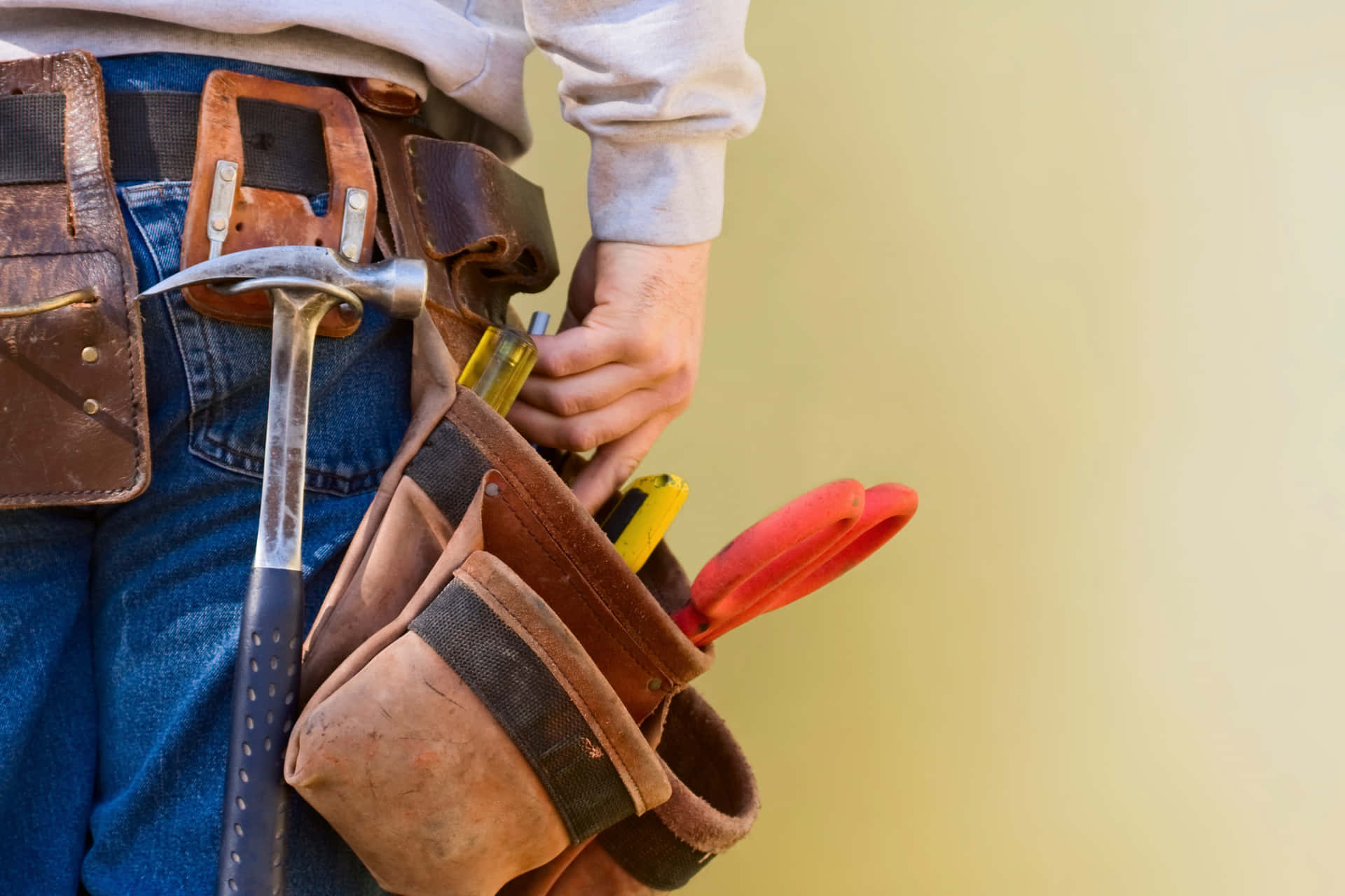 A Man With A Tool Belt Holding Tools