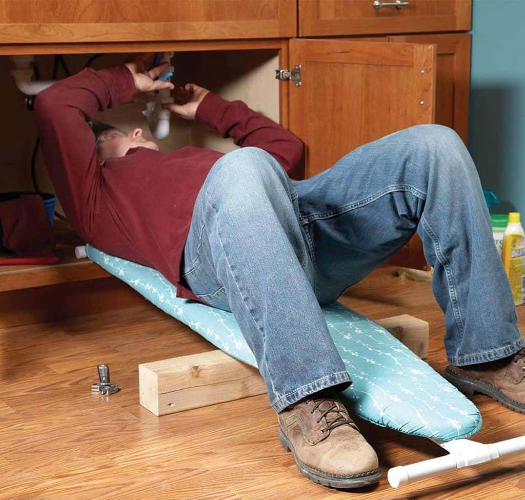 A Man Laying Under A Sink