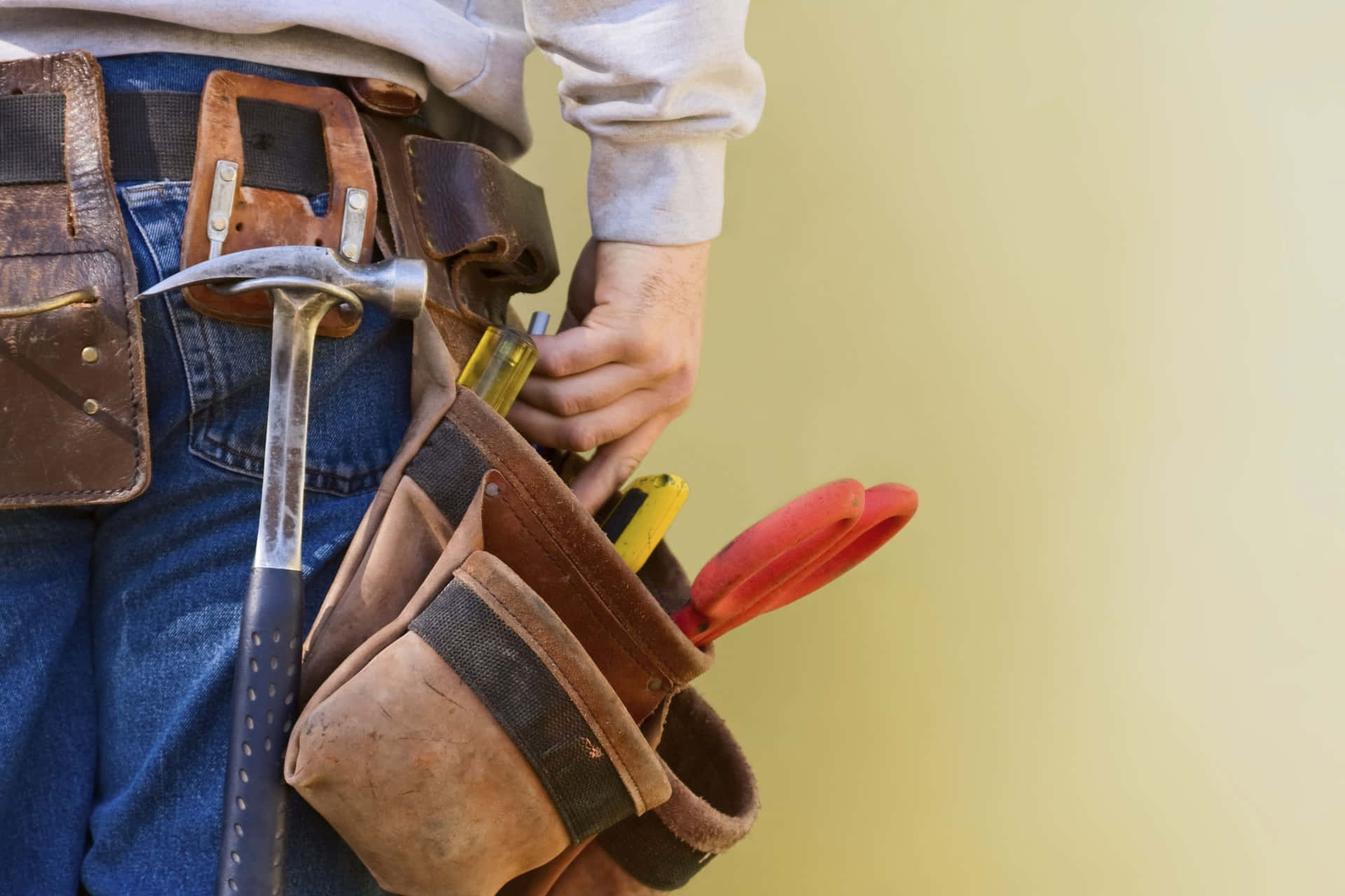 A Man With A Tool Belt Holding Tools