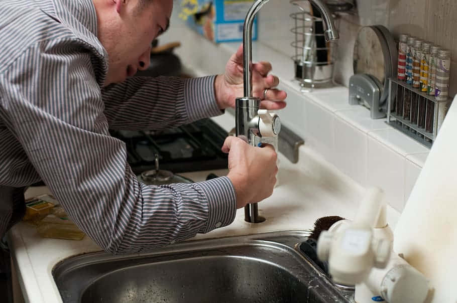 A Man Is Fixing A Sink