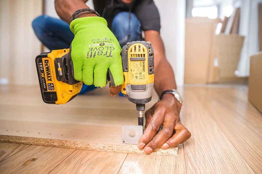 A Man Using A Drill To Install Wood Flooring