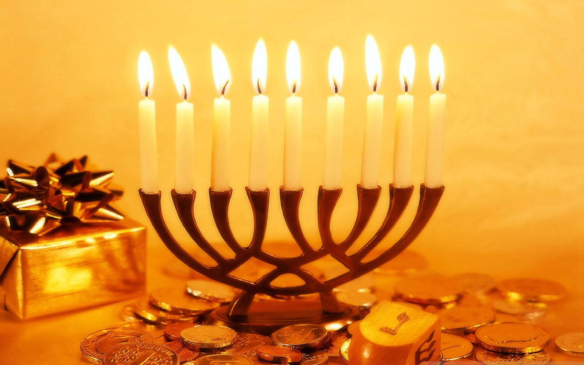 Caption: Illuminating Hanukkah Celebration with Traditional Coins and Candles Wallpaper