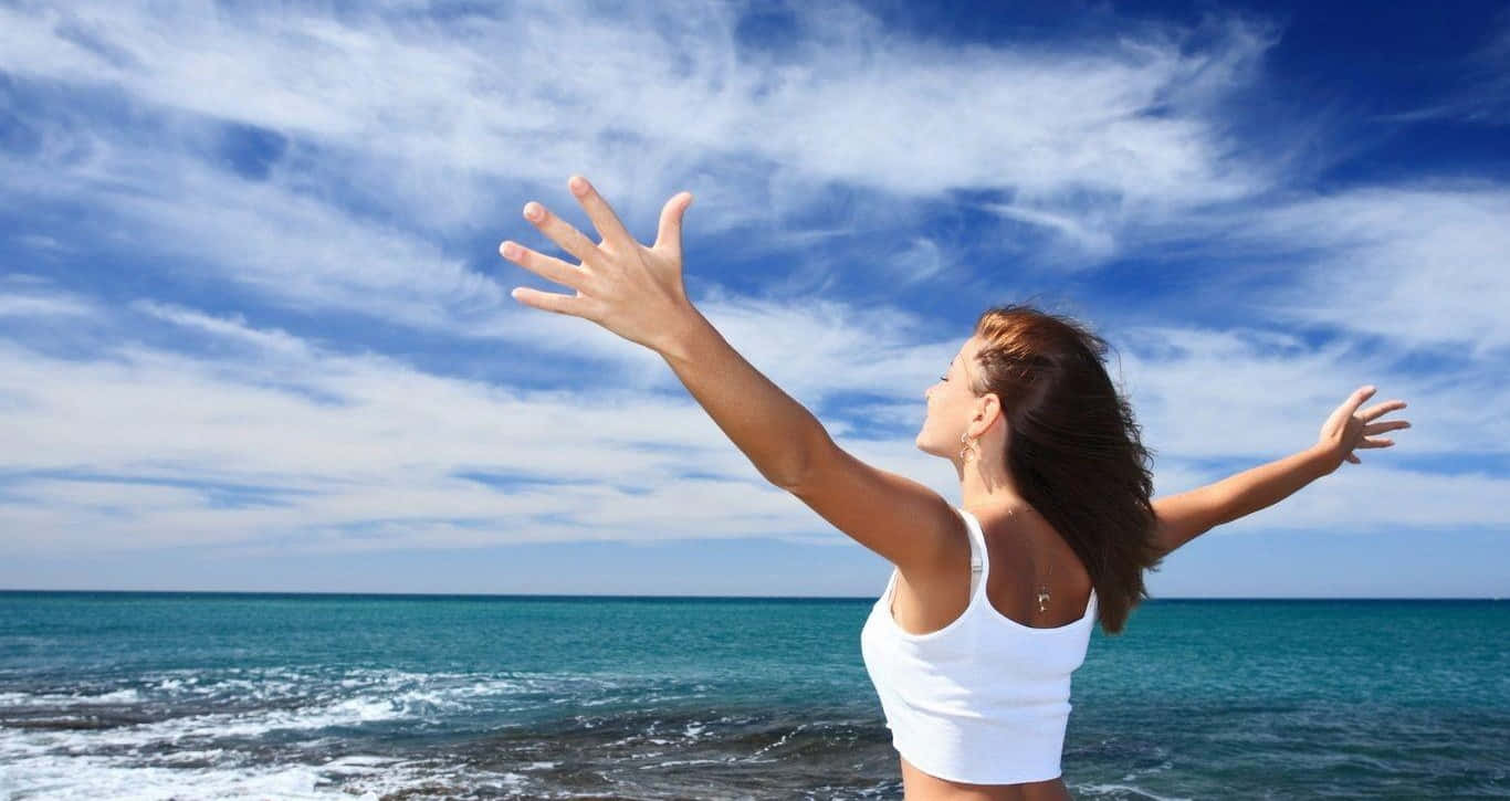 Woman With Arms Outstretched On The Beach