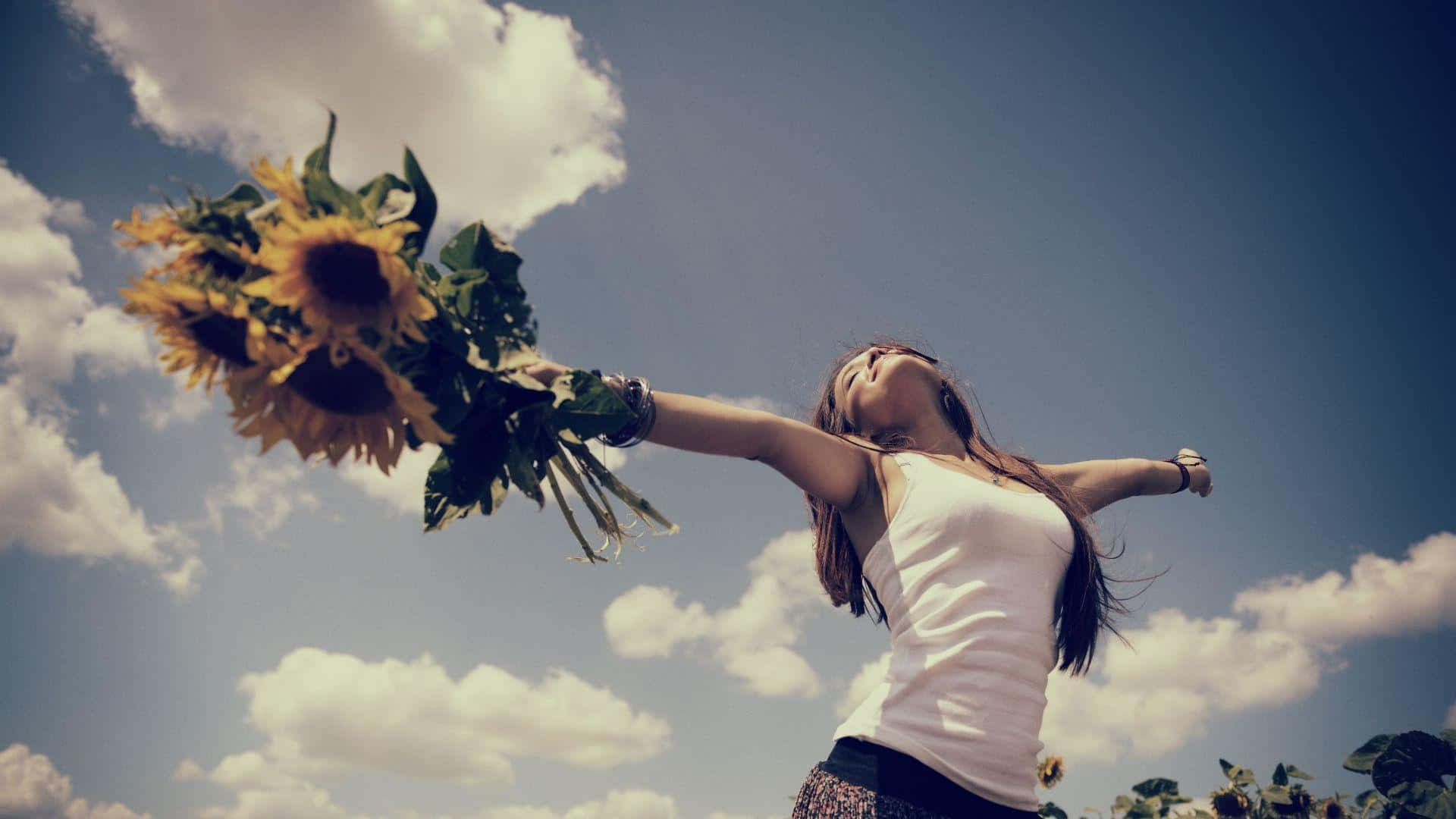 A Woman Is Holding Sunflowers In The Air