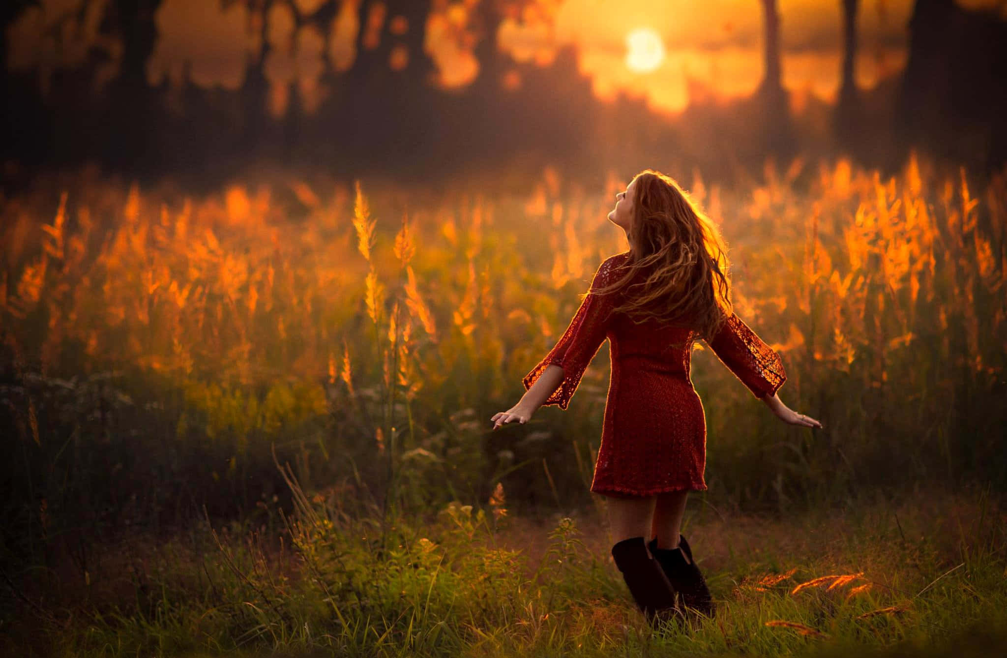 A Woman In Red Standing In A Field At Sunset