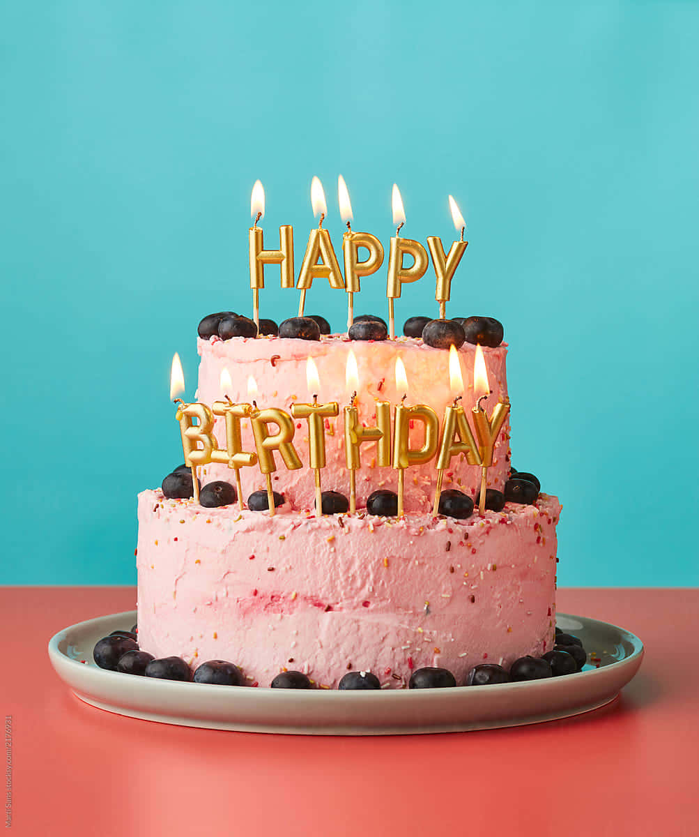 A delicious, colorful Happy Birthday Cake with lit candles and sprinkles.