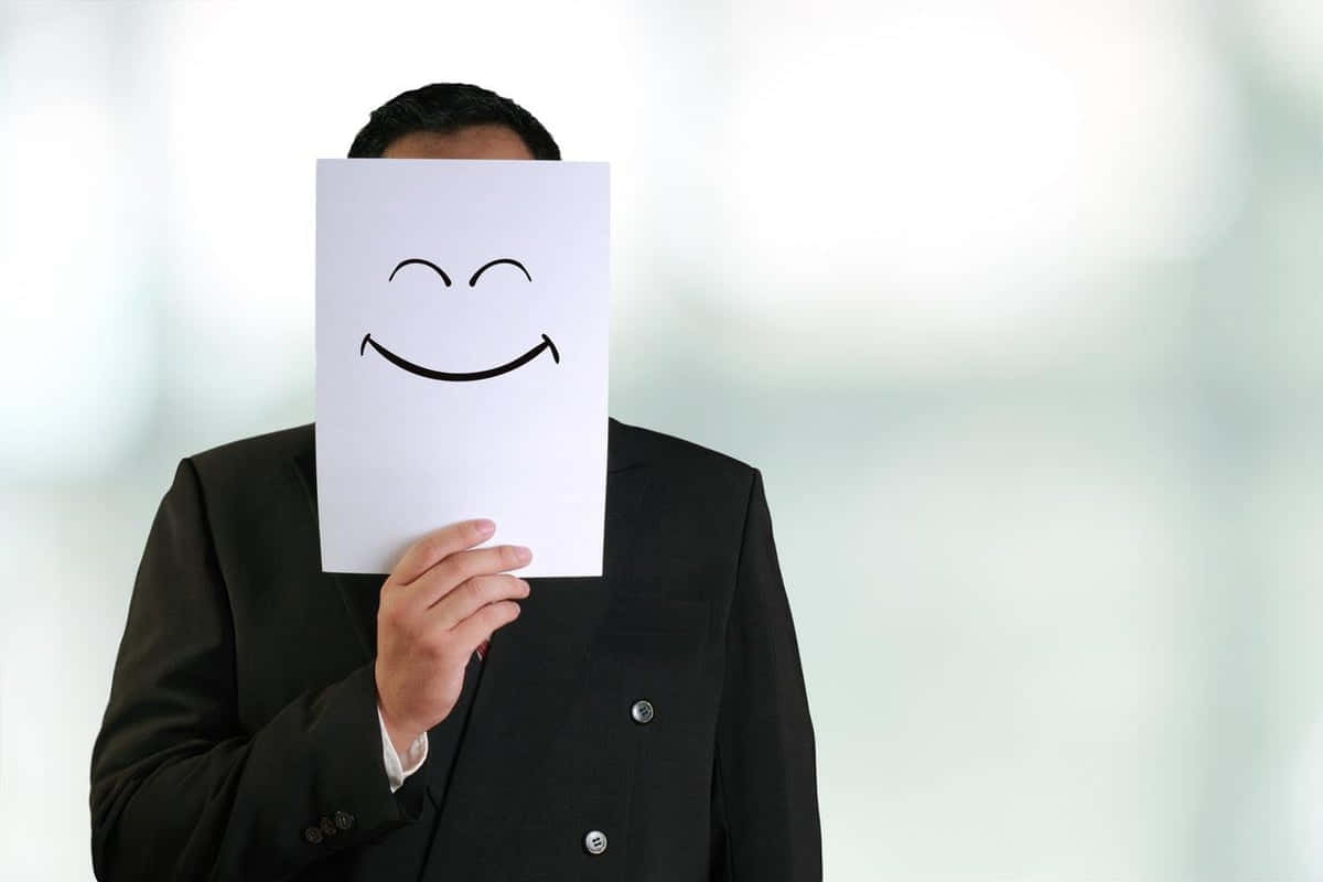 En person, der dækker ansigt med et glad papirbillede